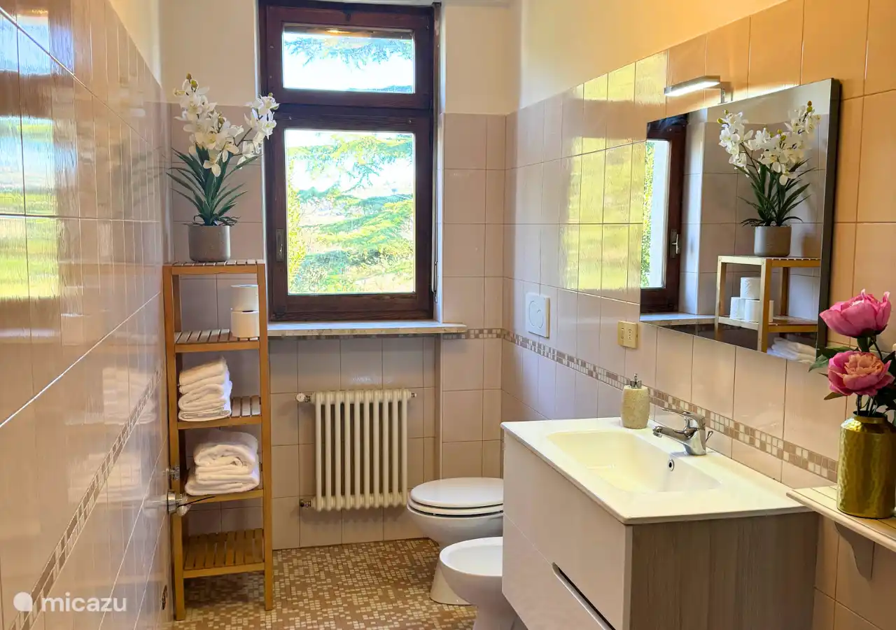 Geräumiges Badezimmer mit Toilette, Bidet, Waschbecken und Dusche.