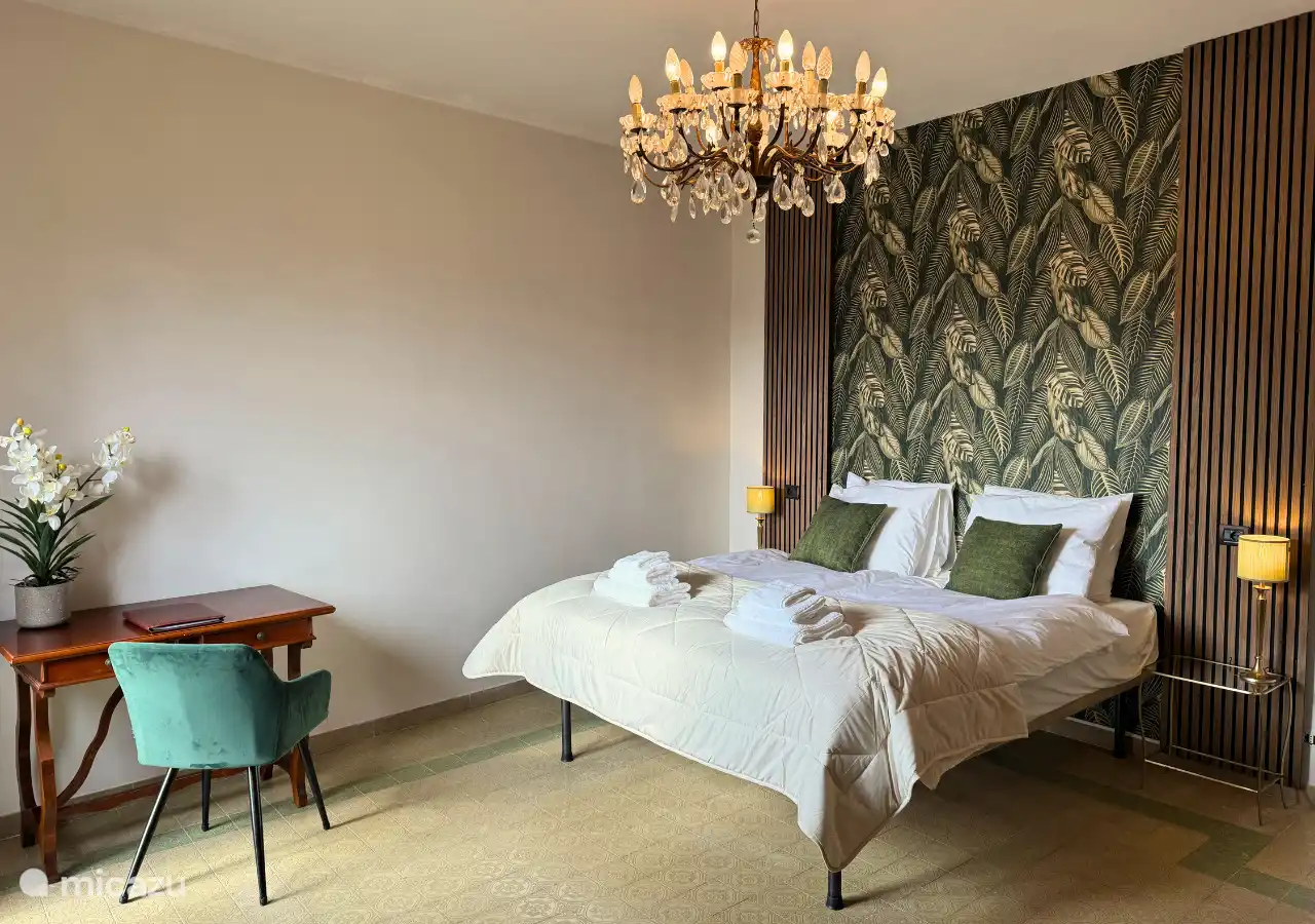 Schlafzimmer 2 mit einem 180 cm breiten Bett bietet Blick auf die Hügel, einen Balkon mit Sitzgelegenheiten, eine Kommode und einen Schreibtisch.