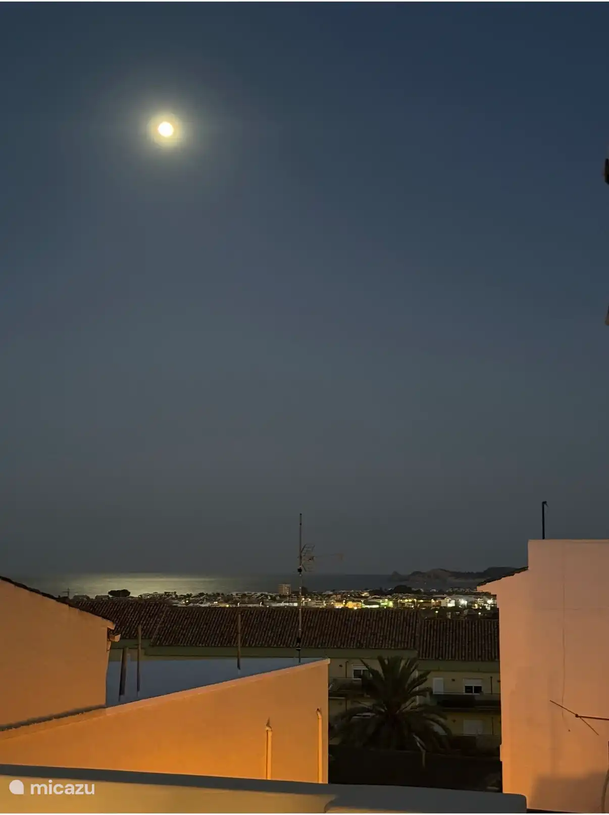 Terrasse sur le toit Casa Loreto la nuit, avec l’éclairage de l’Arenal et la lumière de la lune sur la mer Méditerranée.