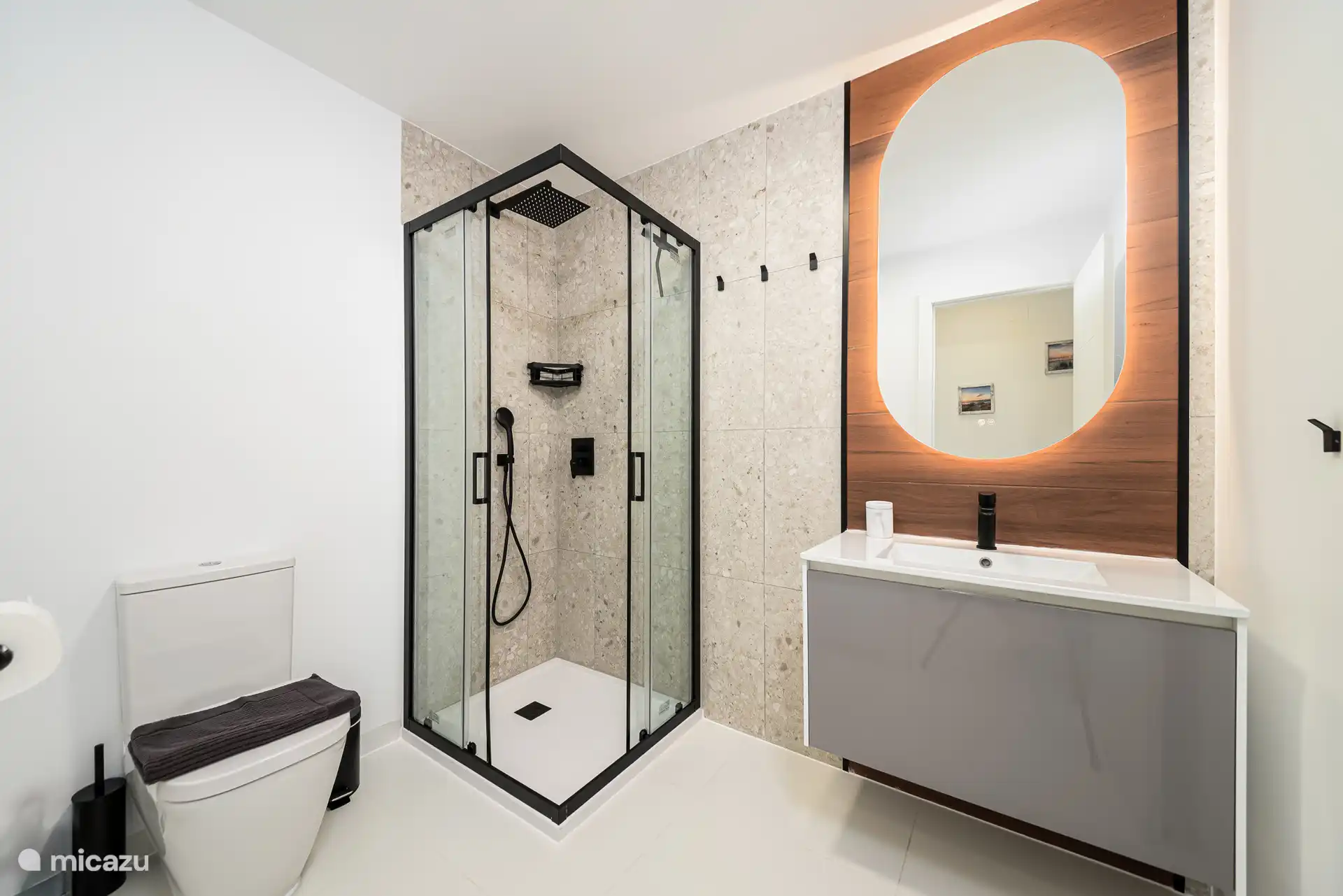 Dos baños con ducha de lluvia, inodoro y lavabo con espejo calefactado e iluminado.