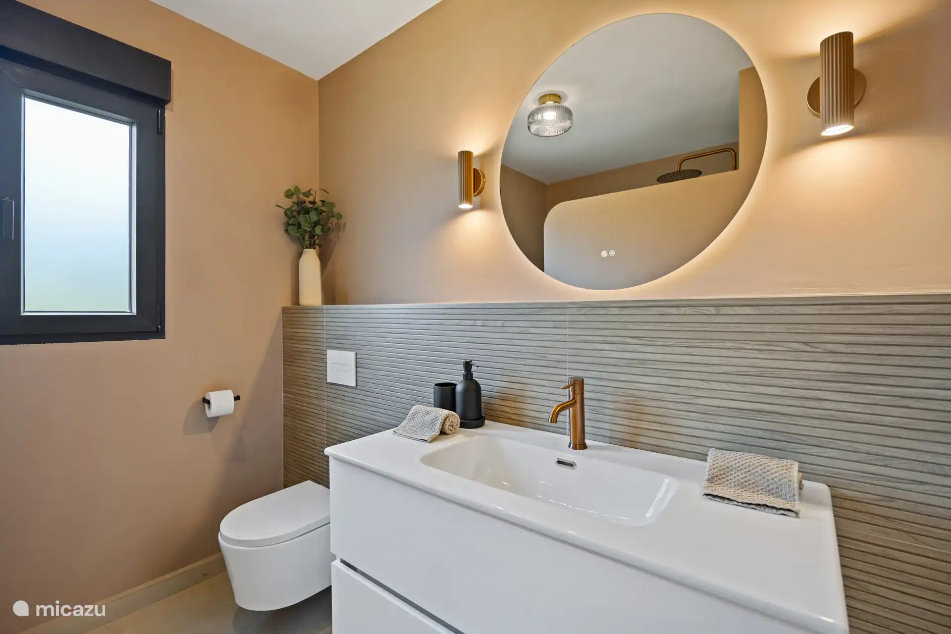 Badkamer met ronde spiegel en gouden accenten — een stijlvolle plek om je klaar te maken voor de dag