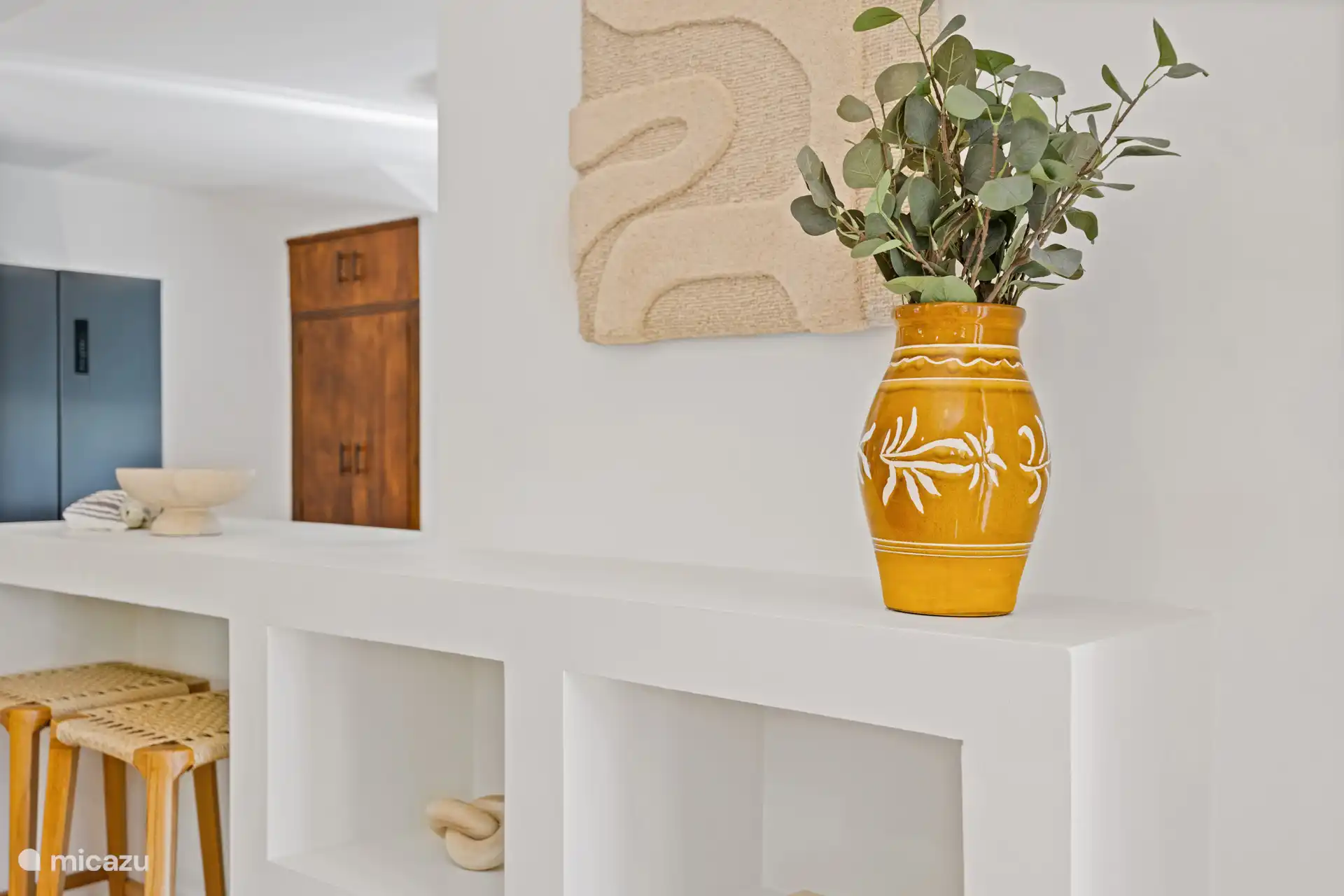 Sfeervolle nis in de woon-eetkamer, met houten deur en decoratieve details — kleine accenten die het verblijf net dat beetje persoonlijker maken