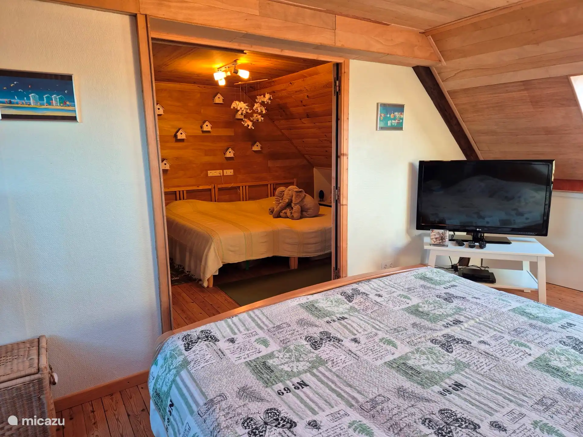 zicht vanuit XXL bed op TV en kinderkamer