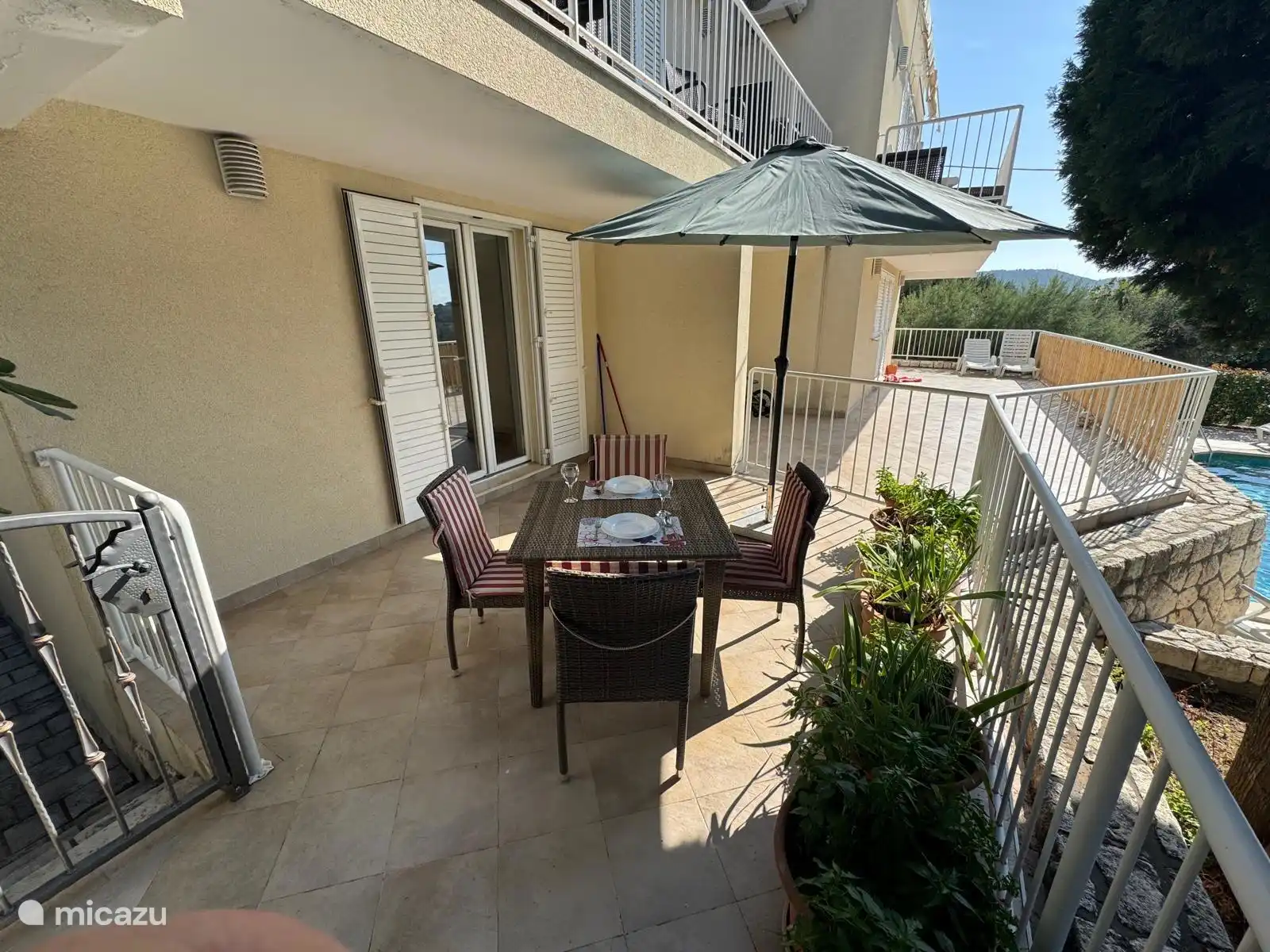 Terraza privada con dos tumbonas privadas para tomar el sol, mesa, cuatro sillas y parasol