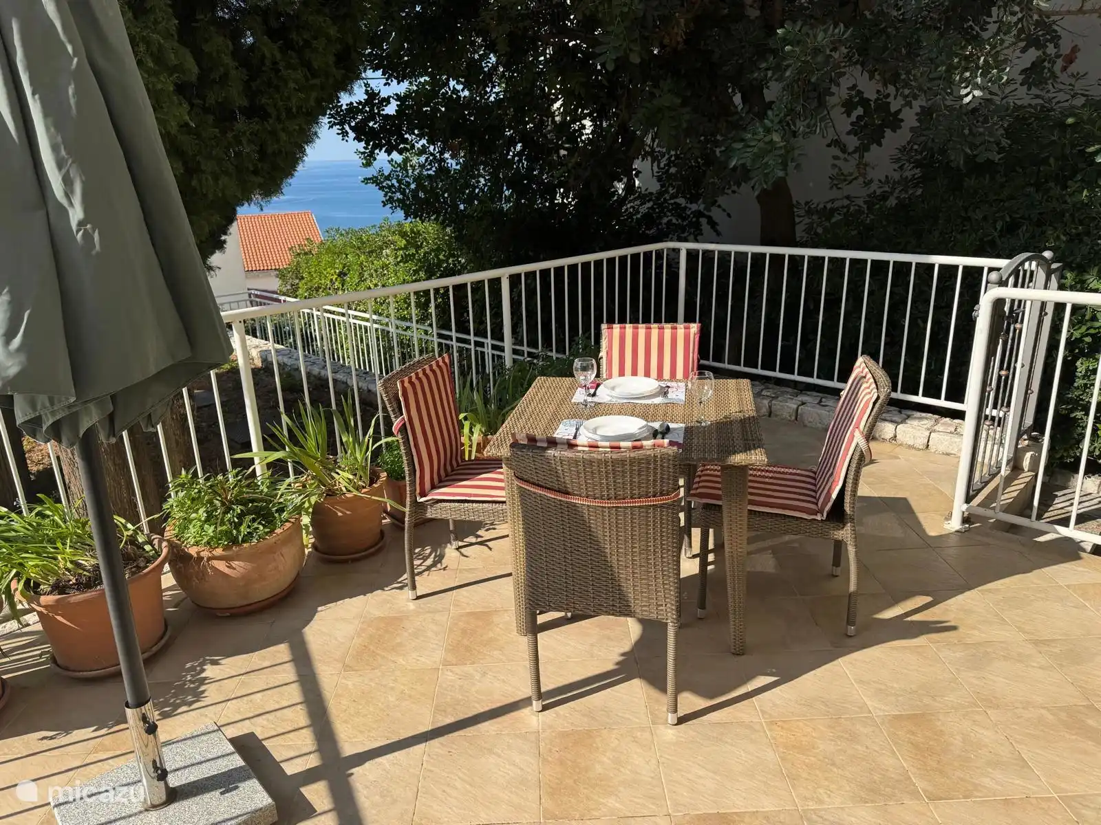 Apartamento Maja con terraza privada con vistas al mar y a la piscina, y sombra junto a árboles. Sol orientado al sur todo el día