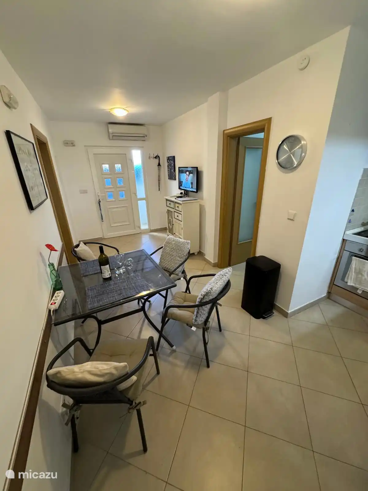 Entrada del apartamento Maja con mesa y cuatro sillas para desayuno, comida o cena, con cocina abierta y televisión