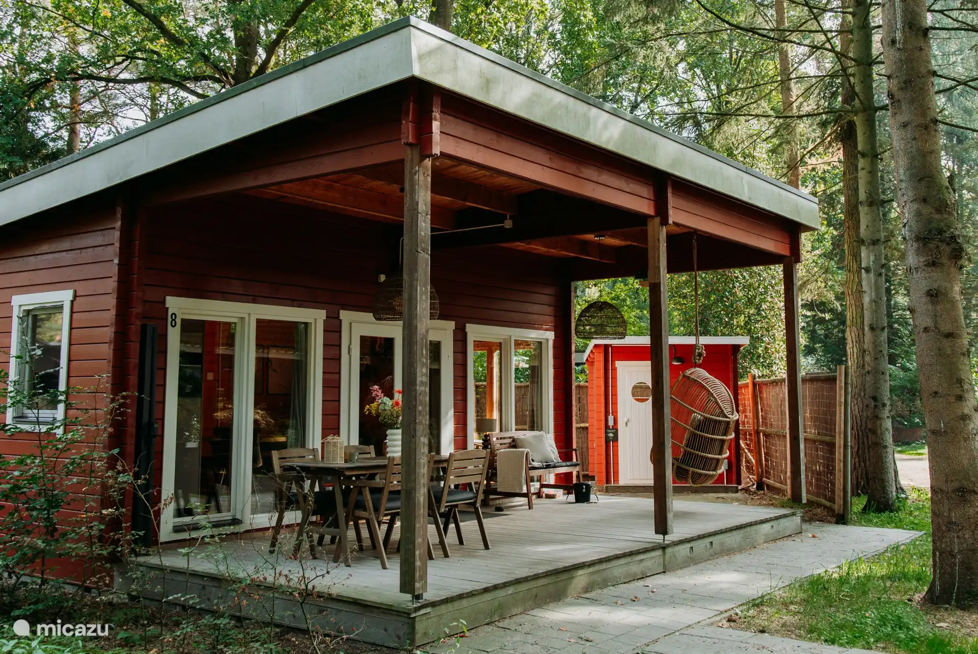 Covered veranda with garden furniture, bench and hanging chair.