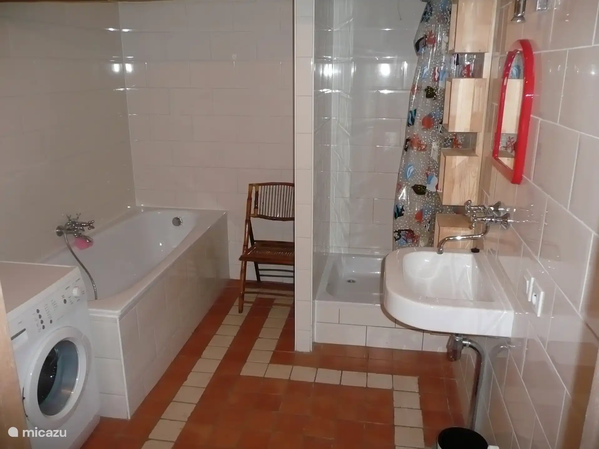 Ruime badkamer met douche, wastafel en ligbad. Hier staat ook de wasmachine. 