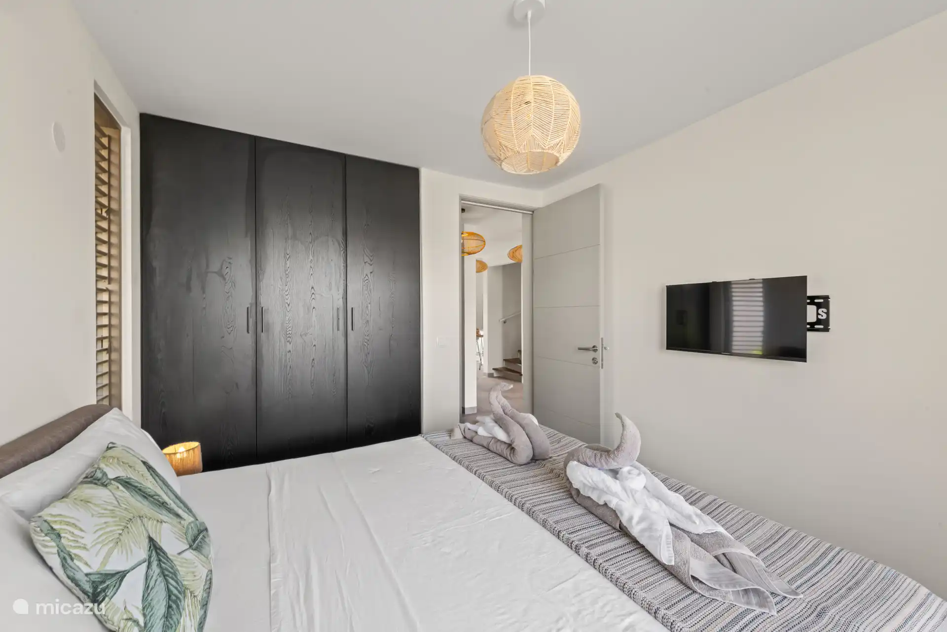 Schlafzimmer 1 mit Doppelbett, privatem Bad, Fernseher, Kleiderschrank und Klimaanlage.