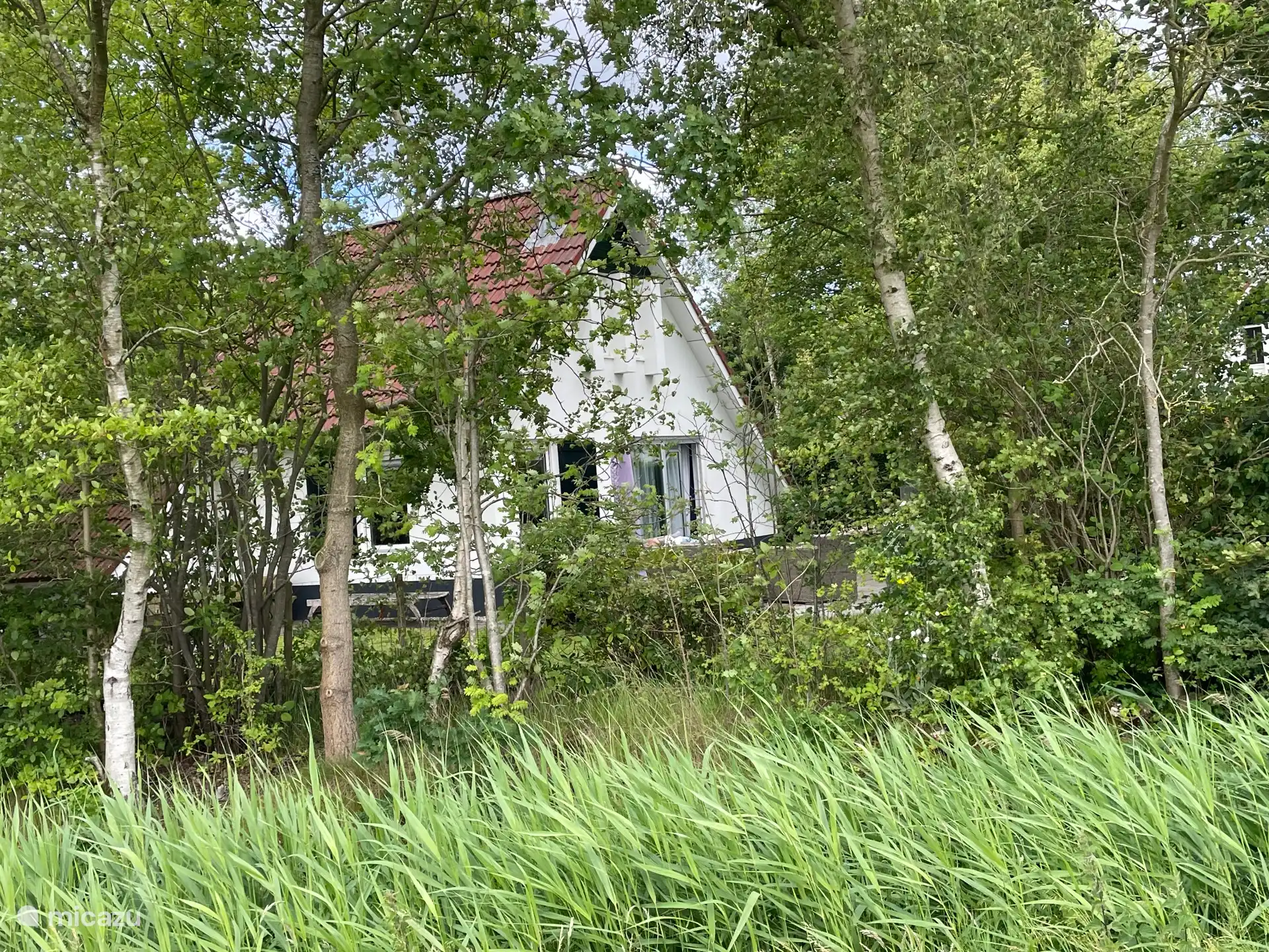L’arrière vu depuis la prairie à côté de la maison. Il y a également des places de parking supplémentaires à cet endroit.