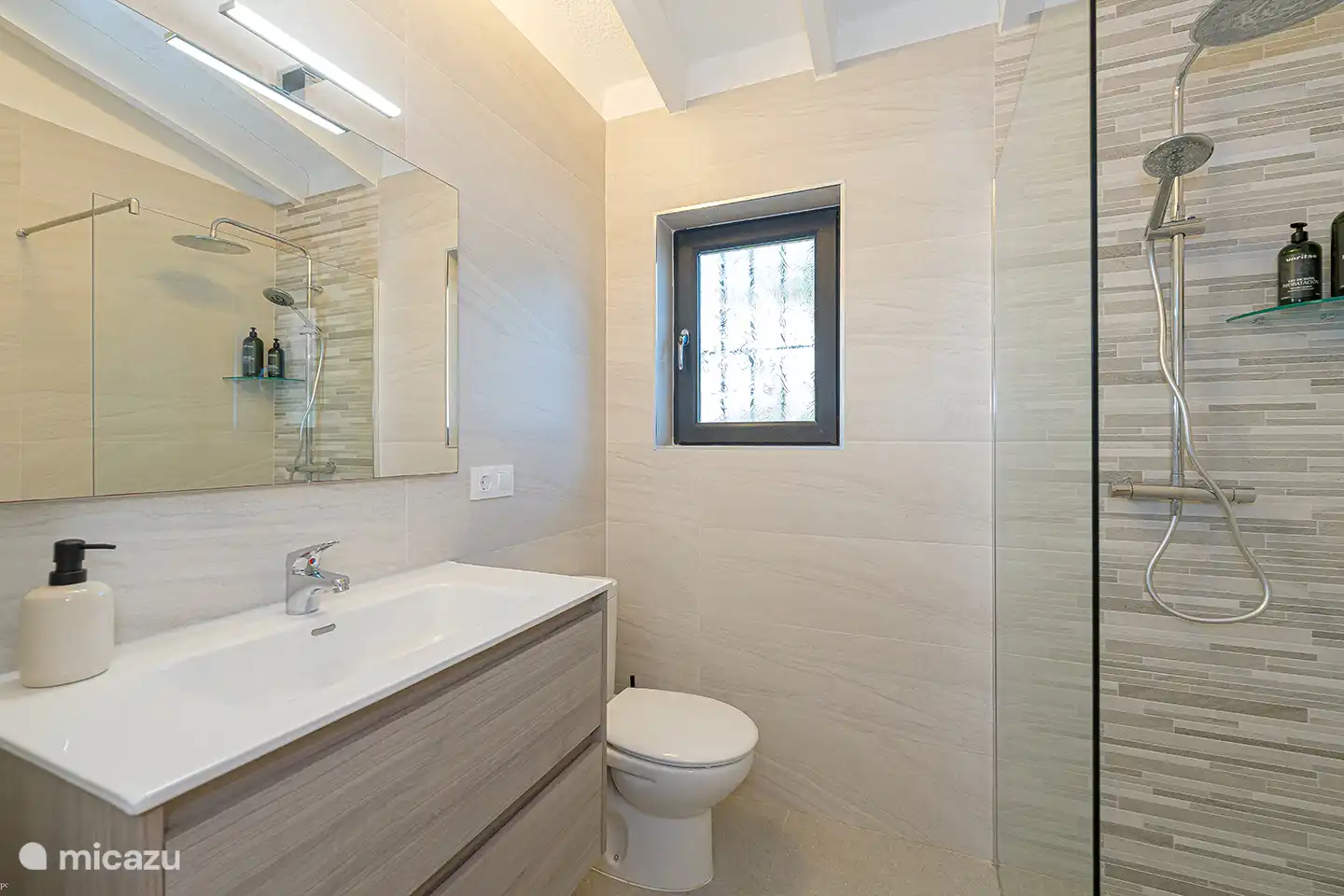 Modernes eigenes Badezimmer mit großzügiger begehbarer Dusche, Waschbecken und Toilette. Alles ist für einen angenehmen Aufenthalt da.