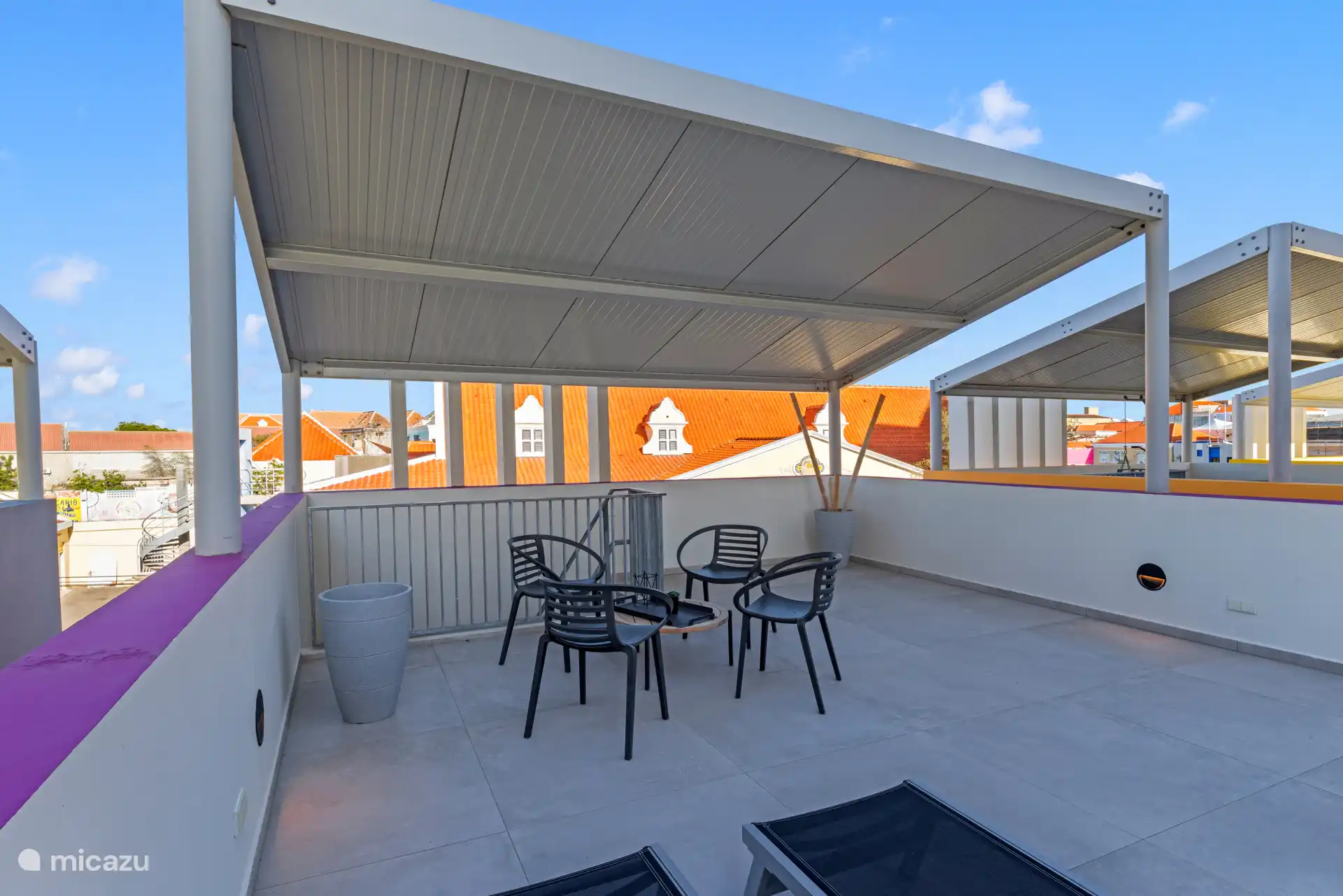 Terraza privada en la azotea con asientos y camas de descanso.