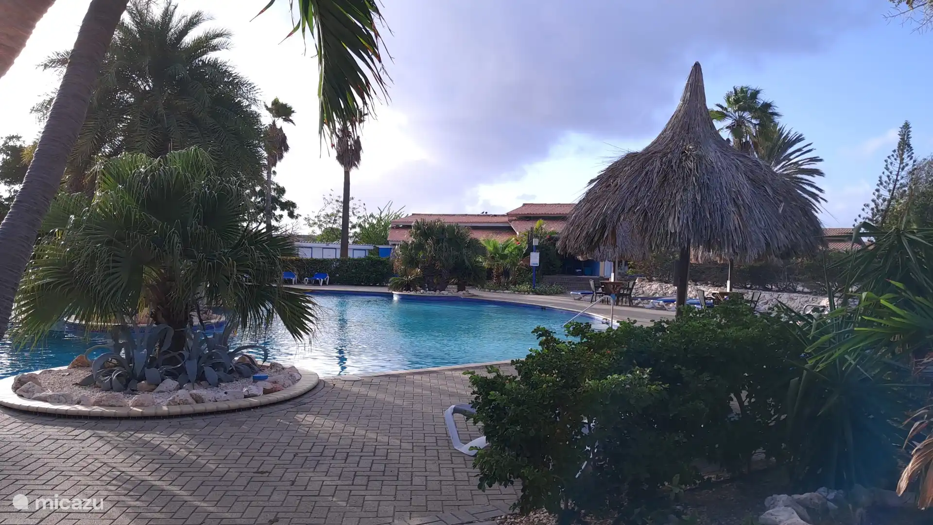 La preciosa piscina con una acogedora sombrilla de palapa durante las horas doradas de la tarde.