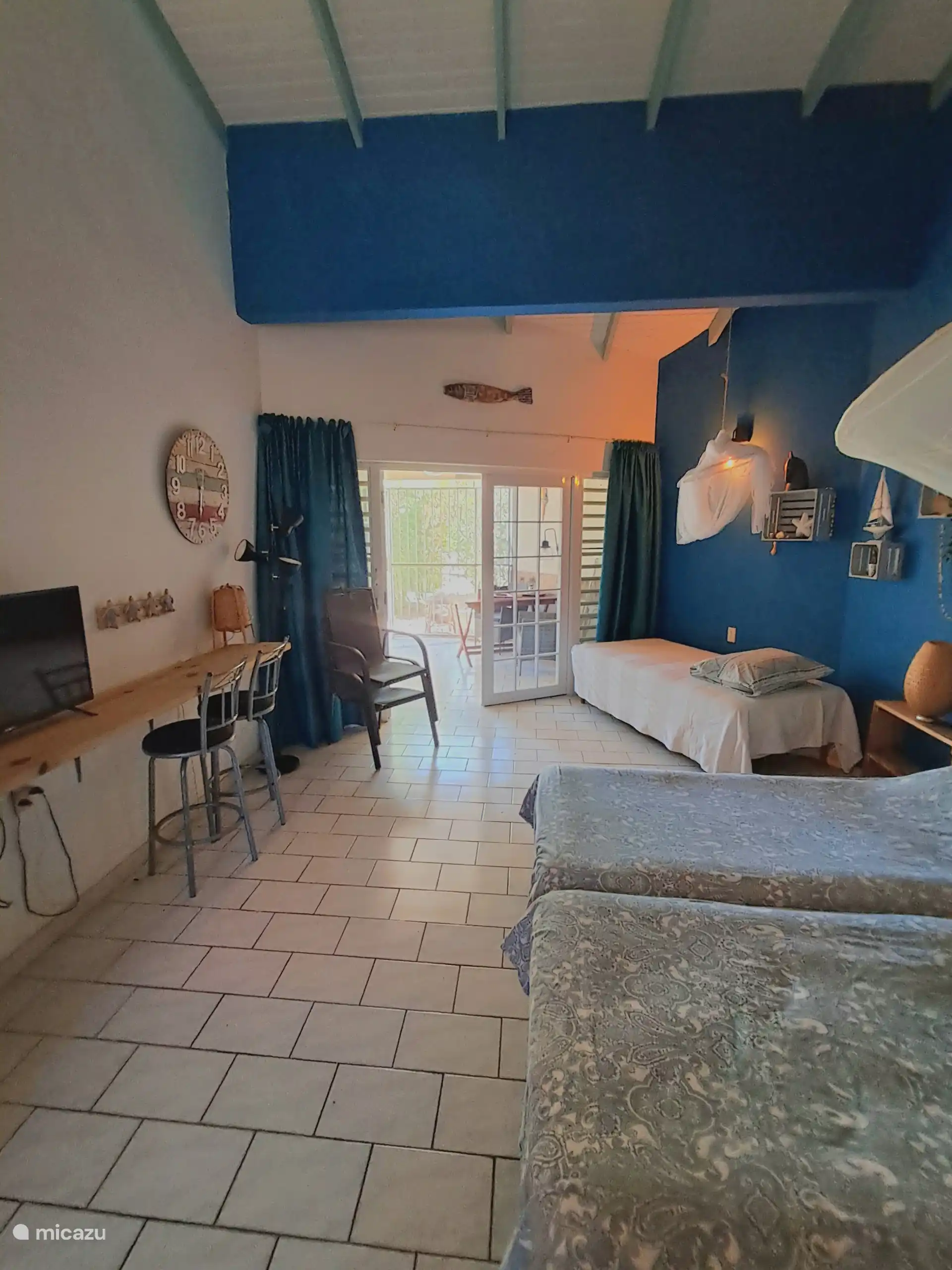 Visión atmosférica del estudio con el bar/lugar de trabajo, la televisión en la pared y el paso a la terraza privada.
