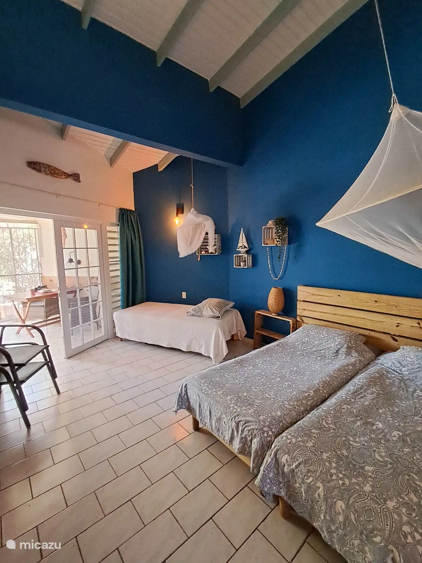 Estudio espacioso y atractivo con una llamativa pared azul intenso, techo de vigas altas y camas cómodas.