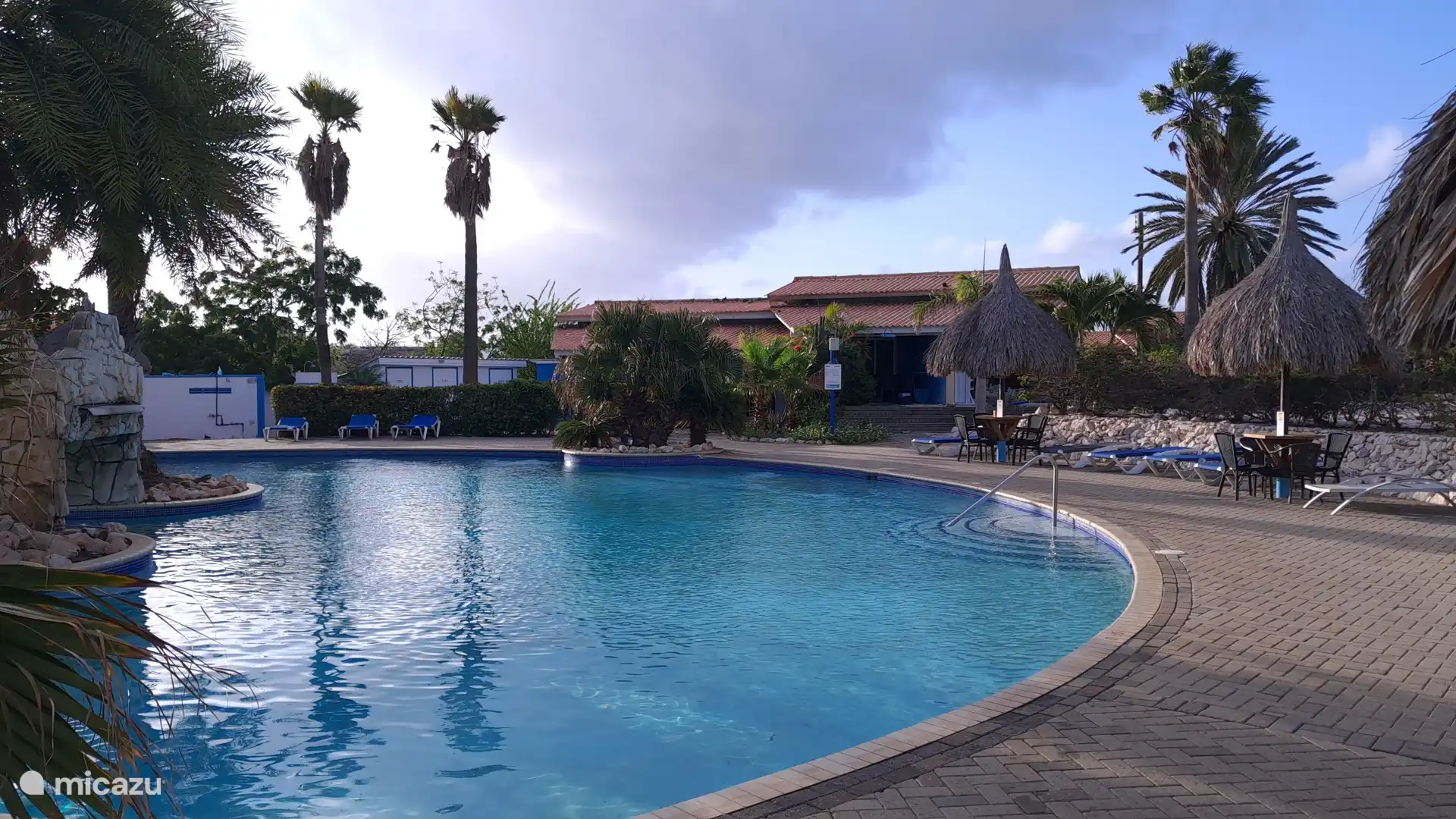 Vistas preciosas sobre la gran piscina del resort con atractivas palapas y plantas tropicales.