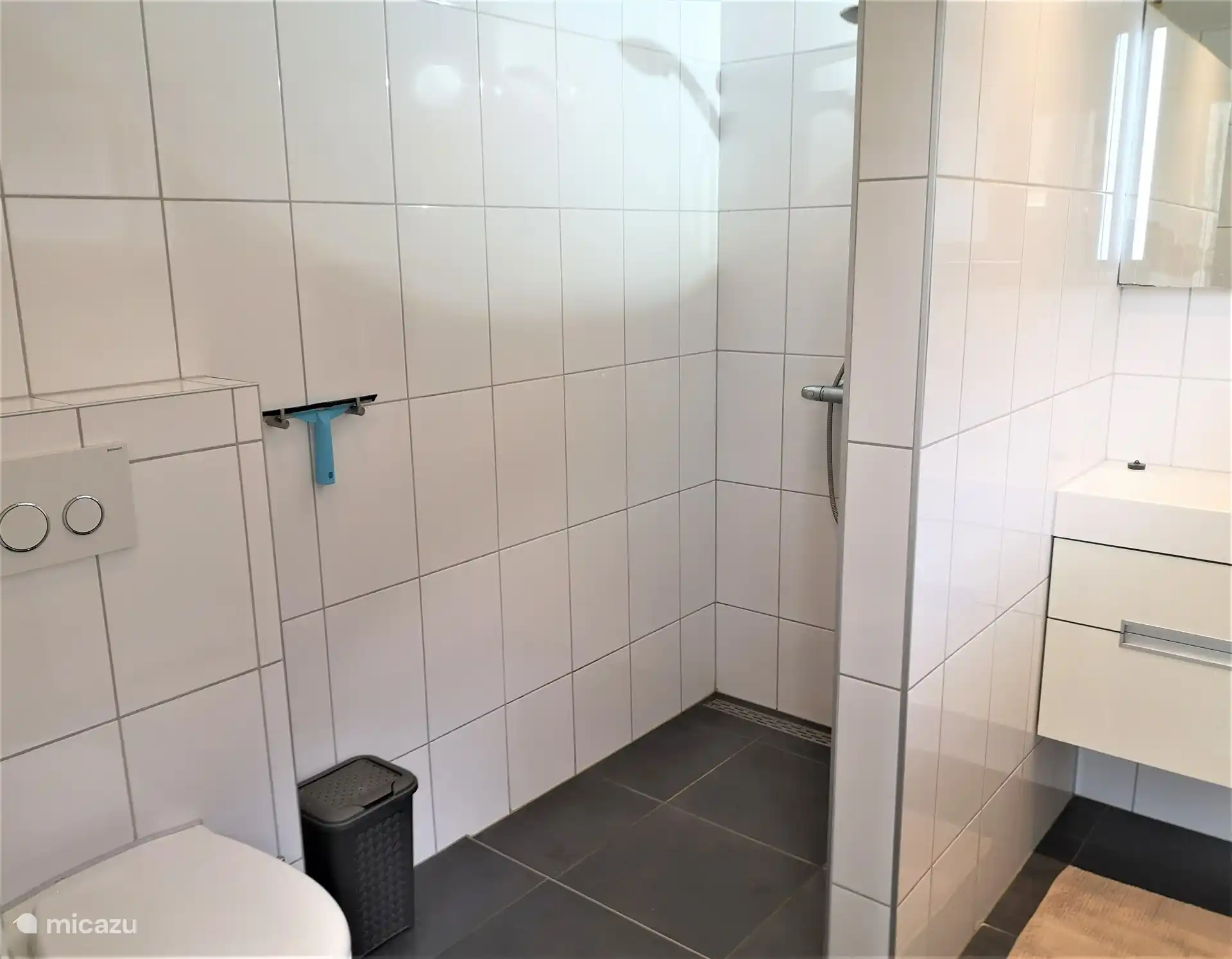 Im Erdgeschoss ist das Badezimmer mit begehbarer Dusche, Waschbecken mit Spiegel, Toilette, Lagerraum und Mülleimer.