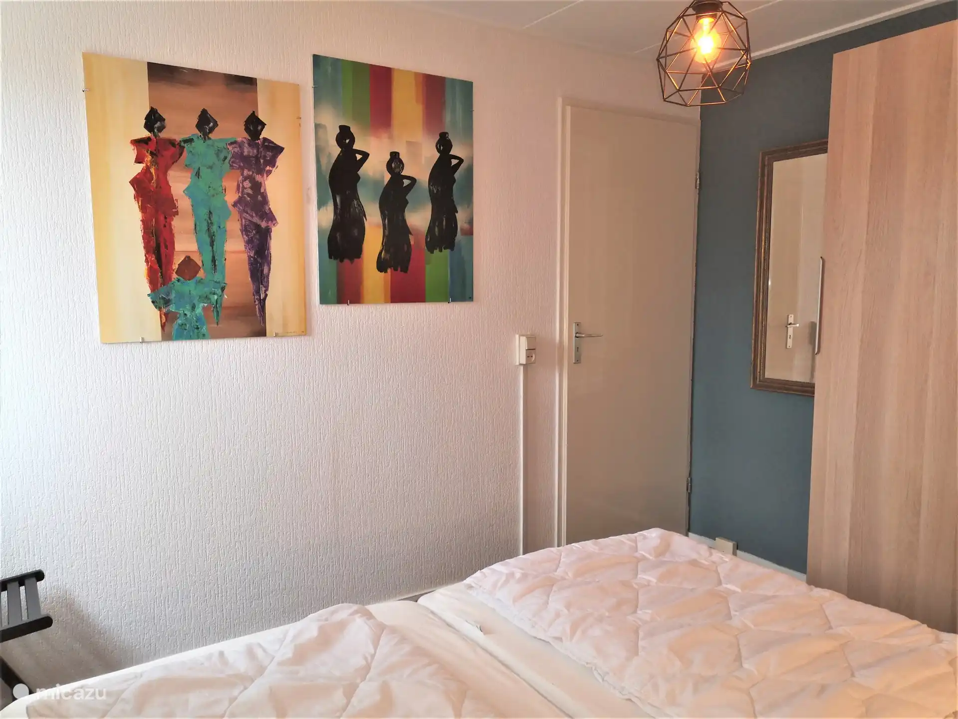 Erdgeschoss mit großem Schlafzimmer, Spiegel, Kleiderschrank, modernen Gemälden.
Die Tür führt in die Küche.