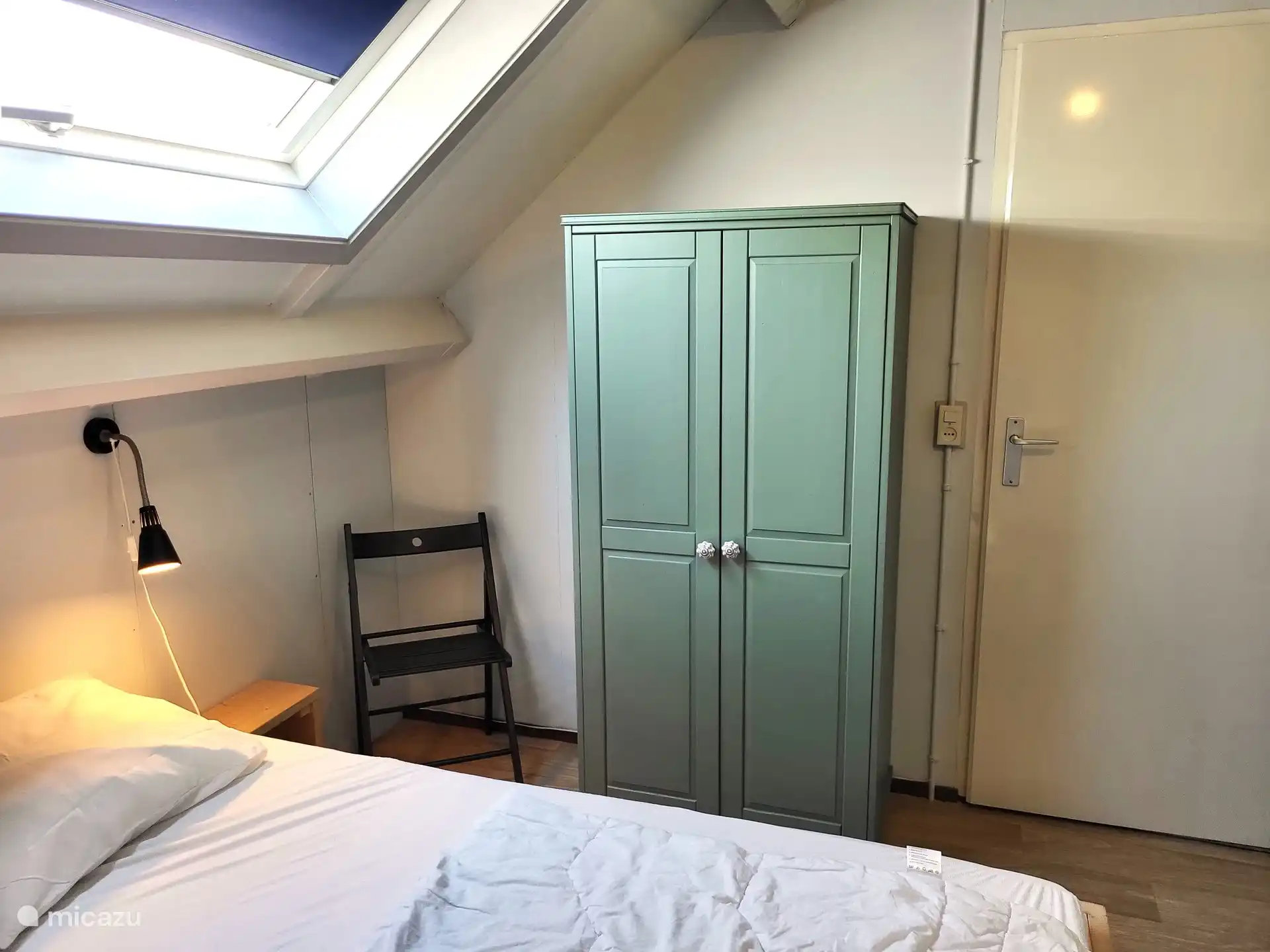 Im ersten Stock großes Schlafzimmer mit Oberlicht und Kleiderschrank, Stuhl.
Die Tür geht zum Treppenabsatz.