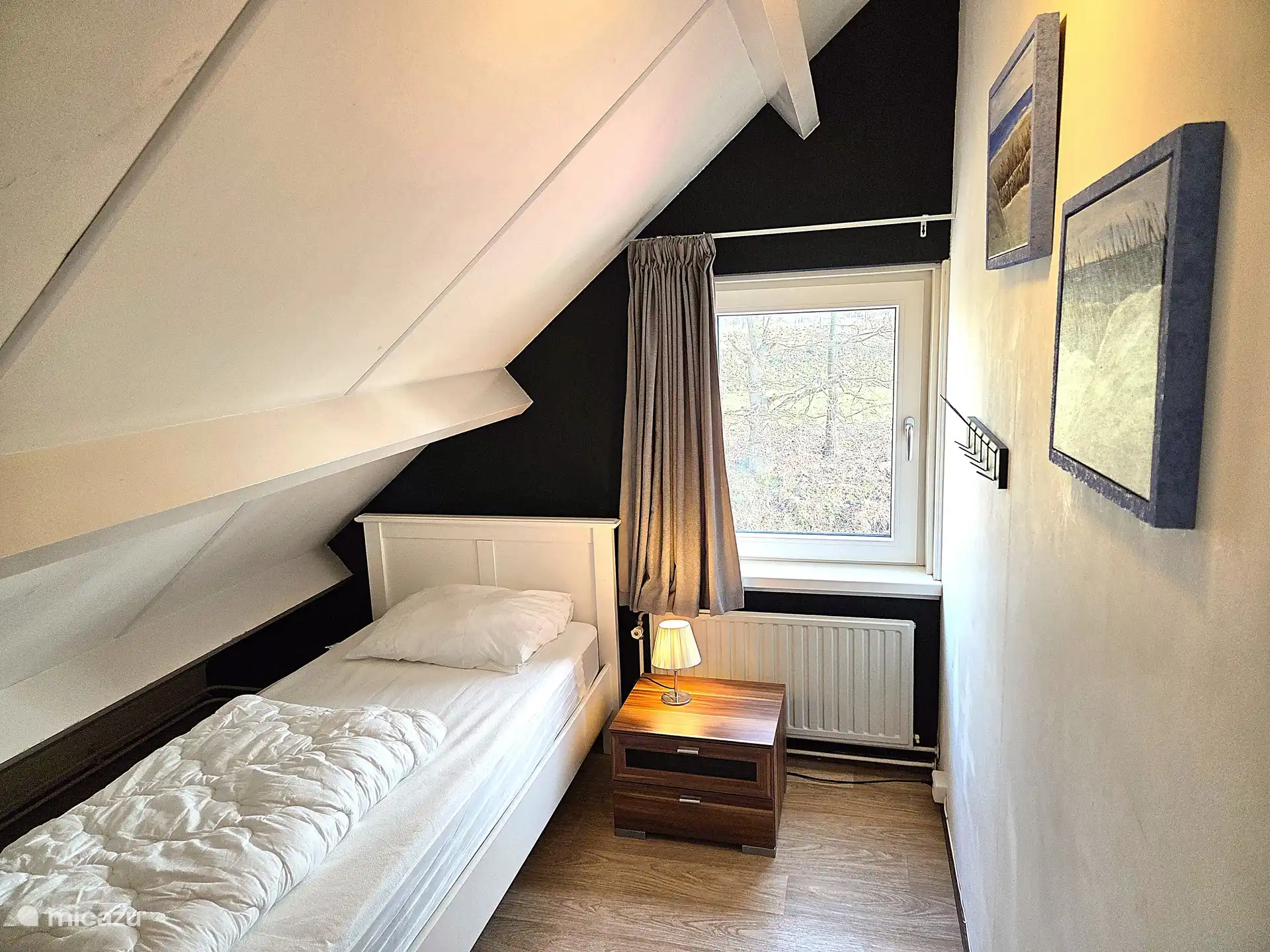 Im ersten Stock ein Einzelbett (90x200) mit Nachttisch, Leselampe, Heizkörper, Bettdecke, Moton, Kissen mit Kissenbezug.
