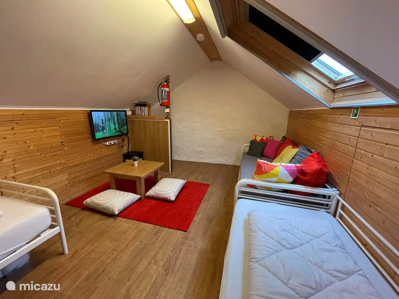 Dormitorio abuhardillado con 2 camas individuales y zona de juegos