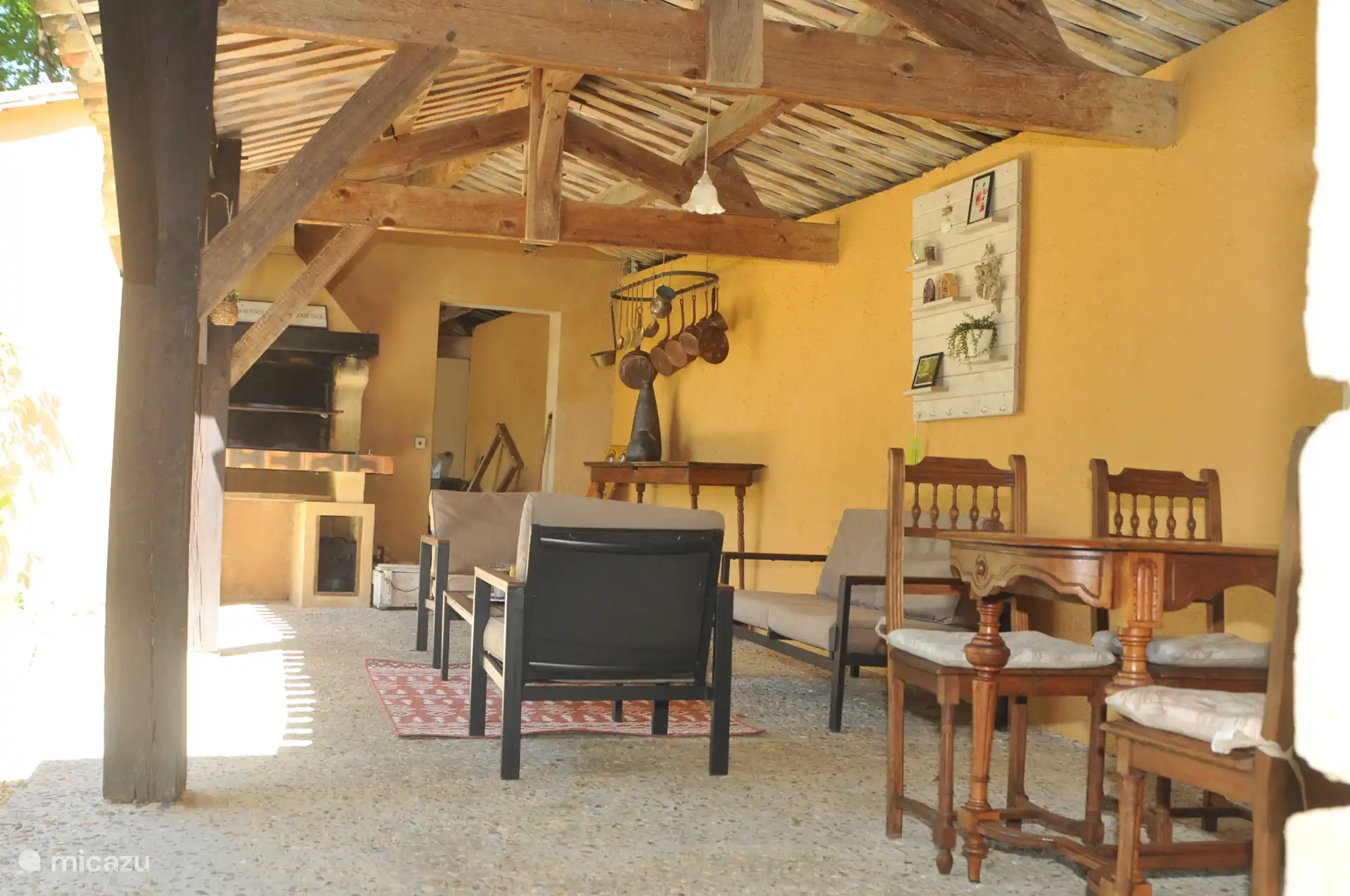 Baldaquin ombragé avec un ensemble de salon et une table à manger avec chaises, adjacent à la cuisine.