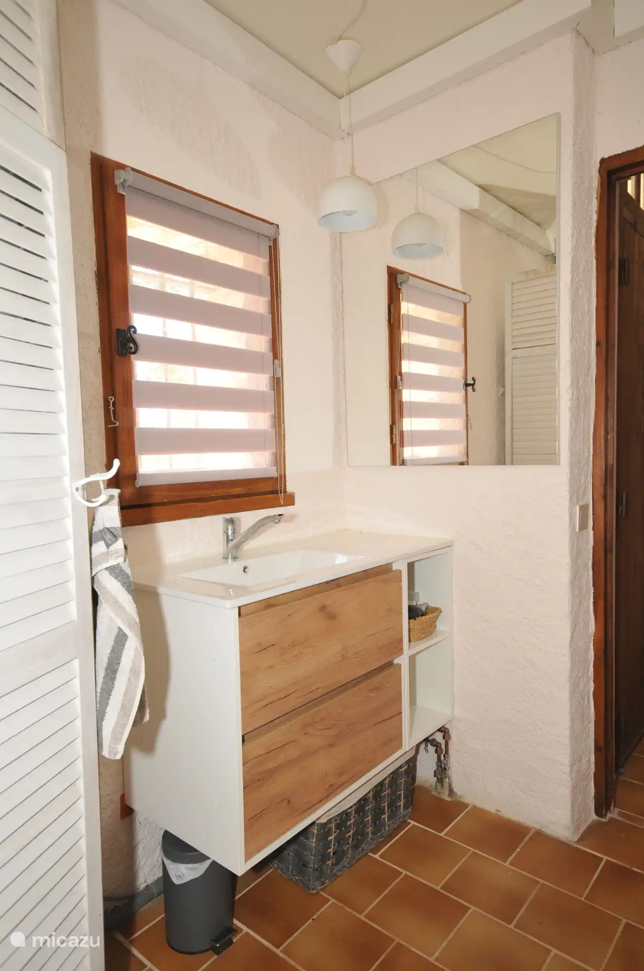 Salle de bain avec lavabo et tiroirs, cabine de douche, machine à laver et toilettes séparées.