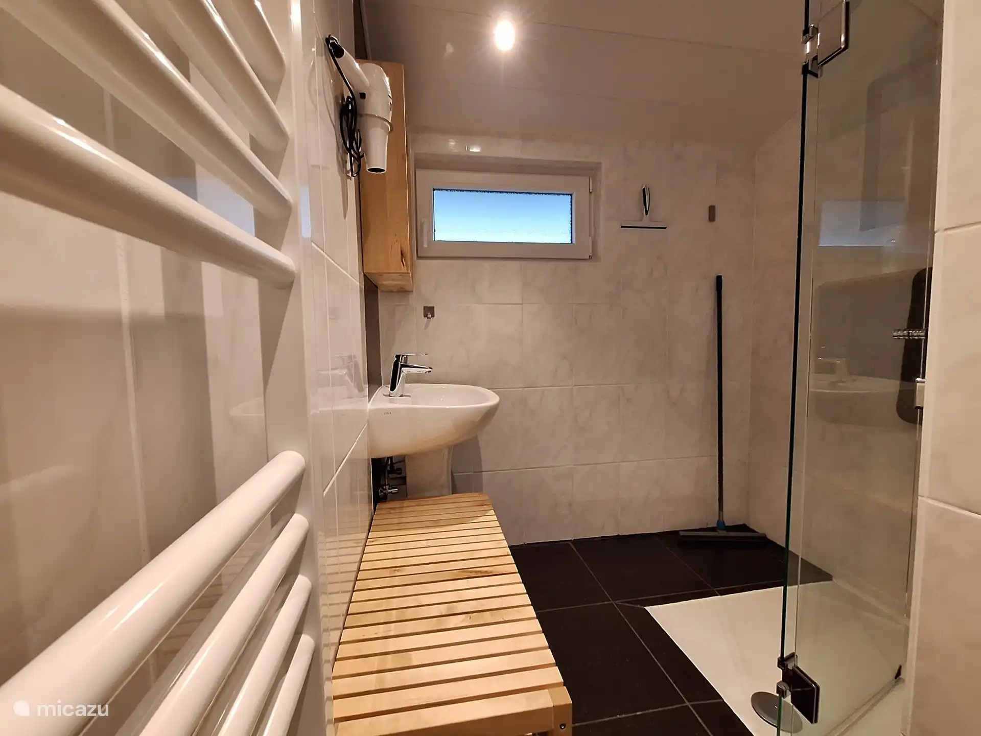 Baño con ducha a pie de piel, lavabo, secador de pelo y banco