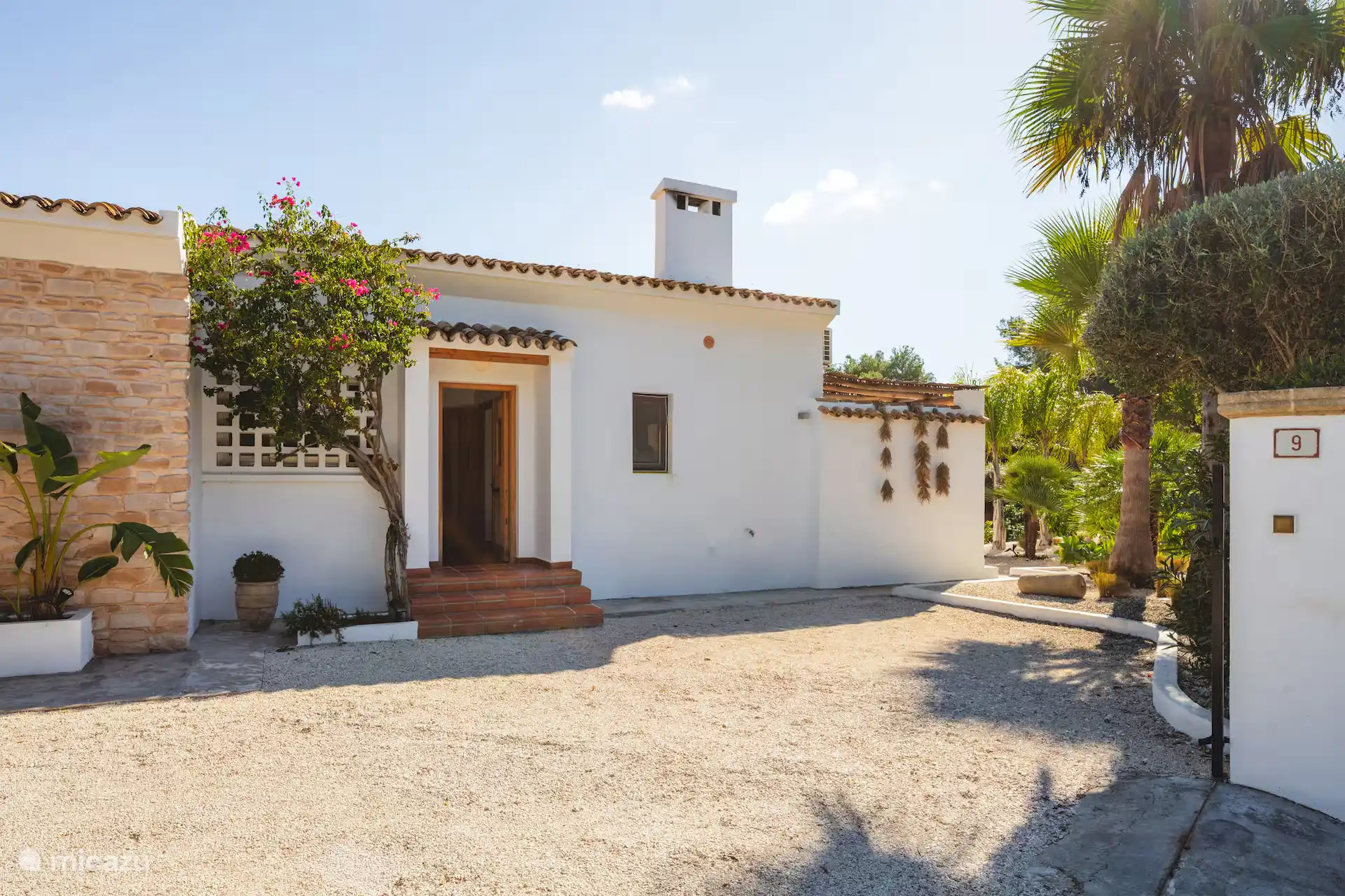La façade de la villa. Il y a un portail et deux voitures peuvent être garées à gauche de la maison. 
