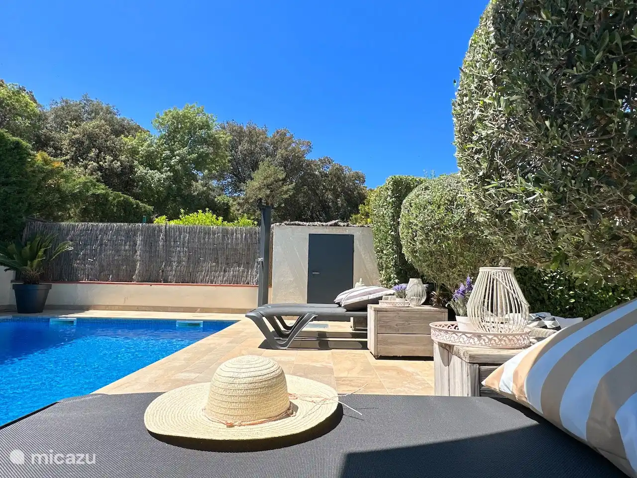 Terrasse ensoleillée avec des chaises longues confortables, des tables de chevet et une clôture complète.