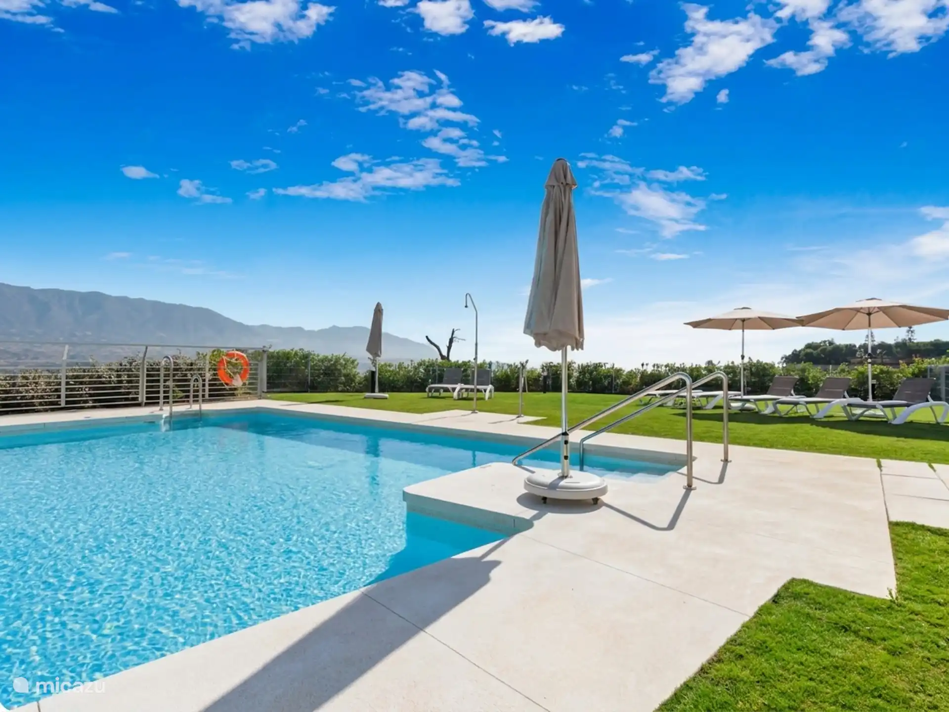 Communal swimming pool with umbrellas and mountain views