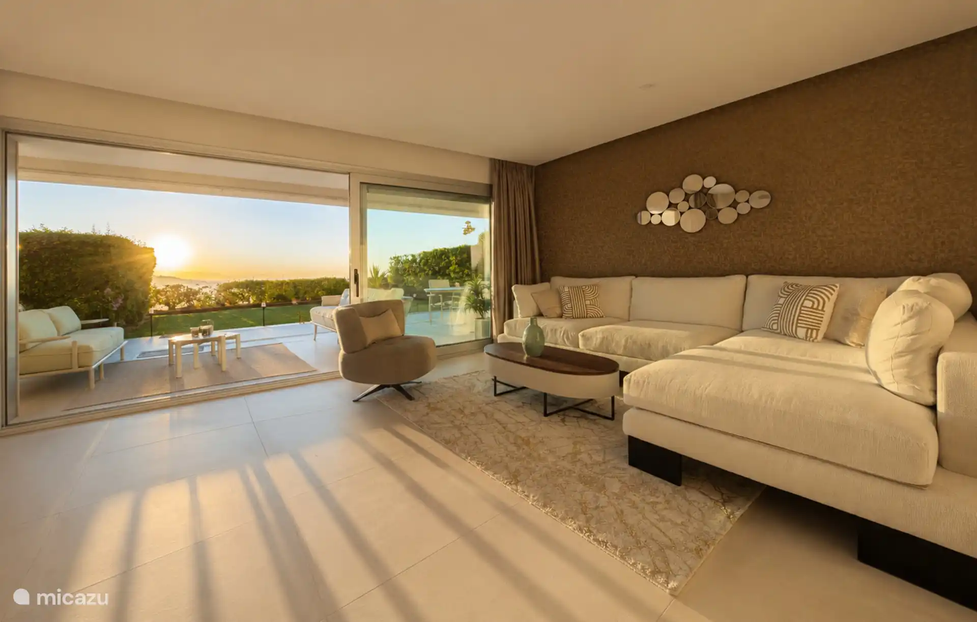 The living room at sunset, with the front completely open to the terrace and garden.