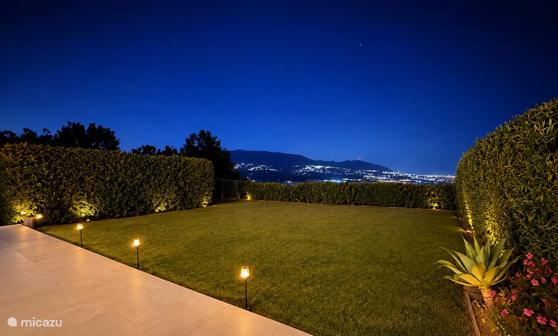 The private garden in the evening, with the lights of the mountain villages and the coast on the horizon.