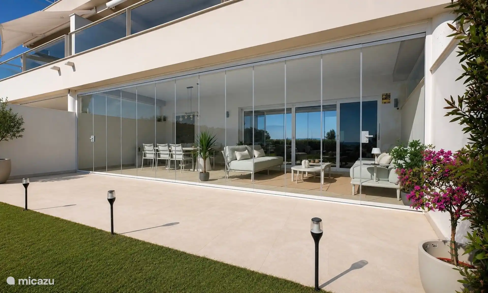 The terrace can be closed with sliding glass walls, so that you can sit comfortably even in the wind or on cooler evenings. Behind it the dining table and the sitting area.
