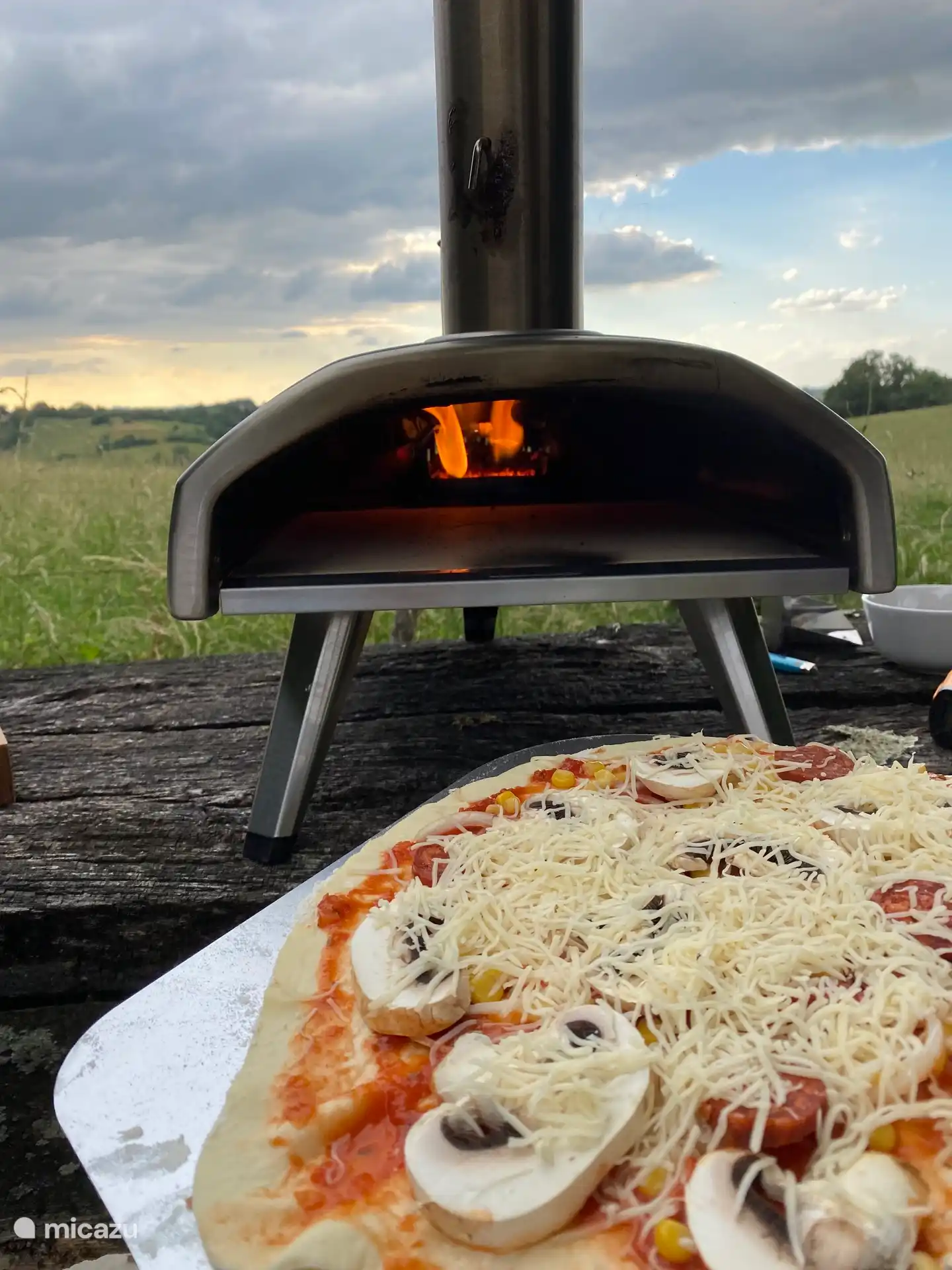 Bereiten Sie Ihre eigenen Pizzen in unserem Ooni-Pizzaofen vor und haken Sie sie ein.