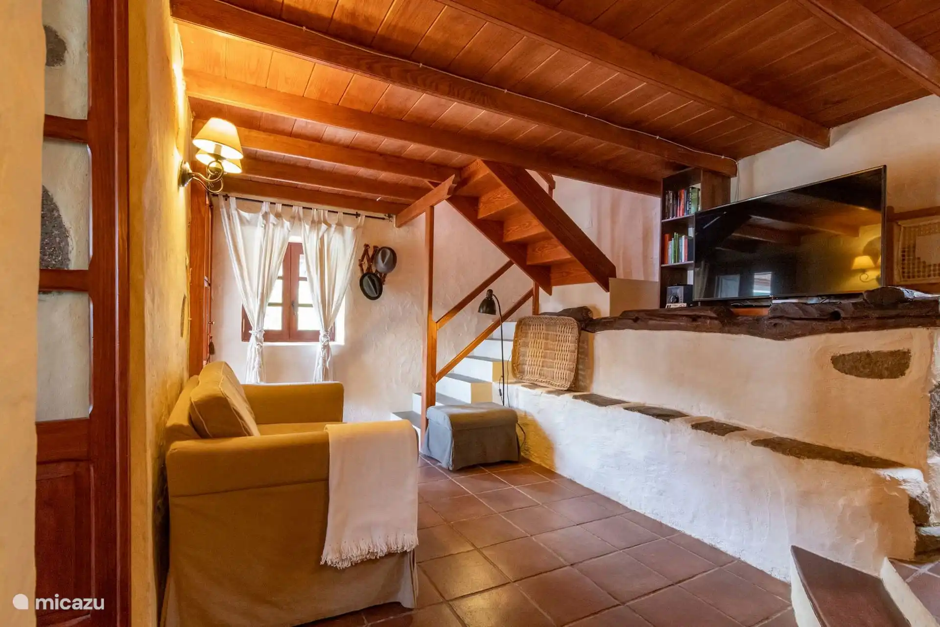 Woonkamer met trap naar de mezzanine en houtgestookte open haard