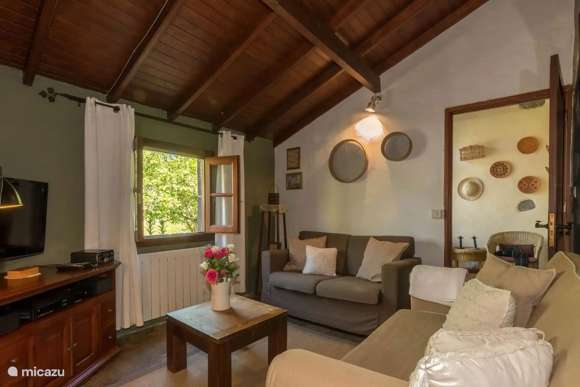 Woonkamer met houten plafond, bank en tv, rustieke Canarische decoratie