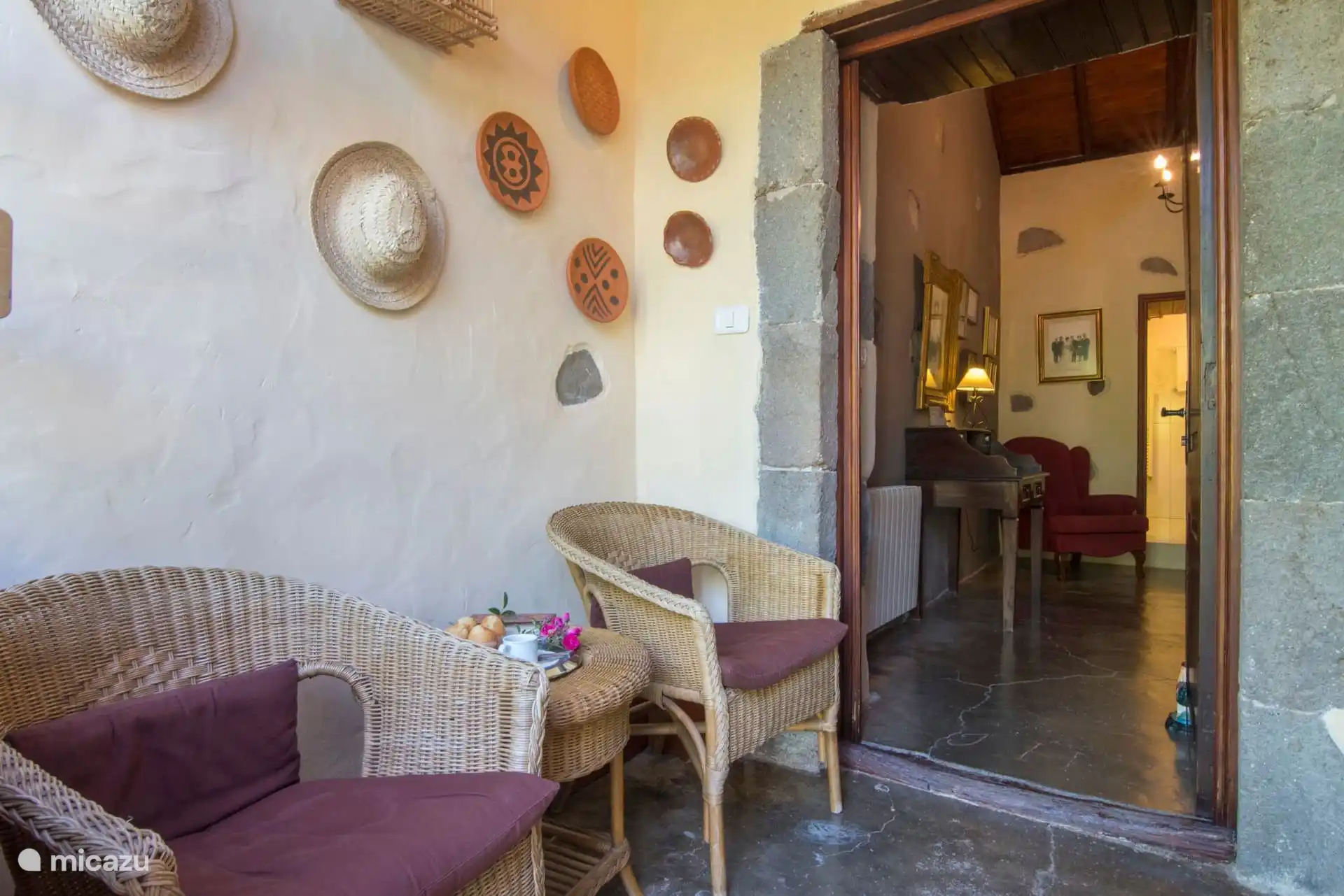 Entreeportaal met rotan fauteuils en decoratieve Canarische borden