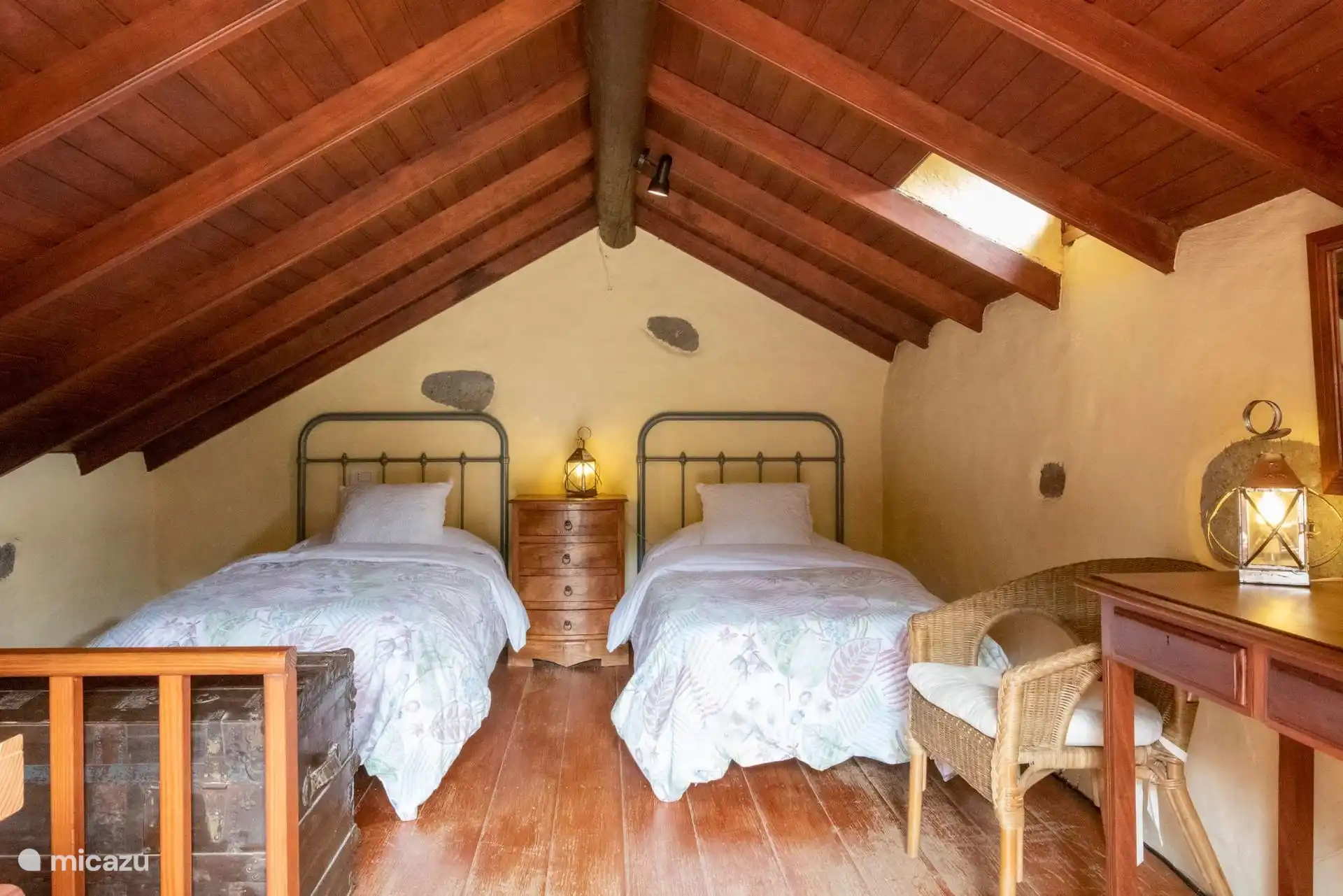Slaapkamer met twee eenpersoonsbedden en een schuin plafond