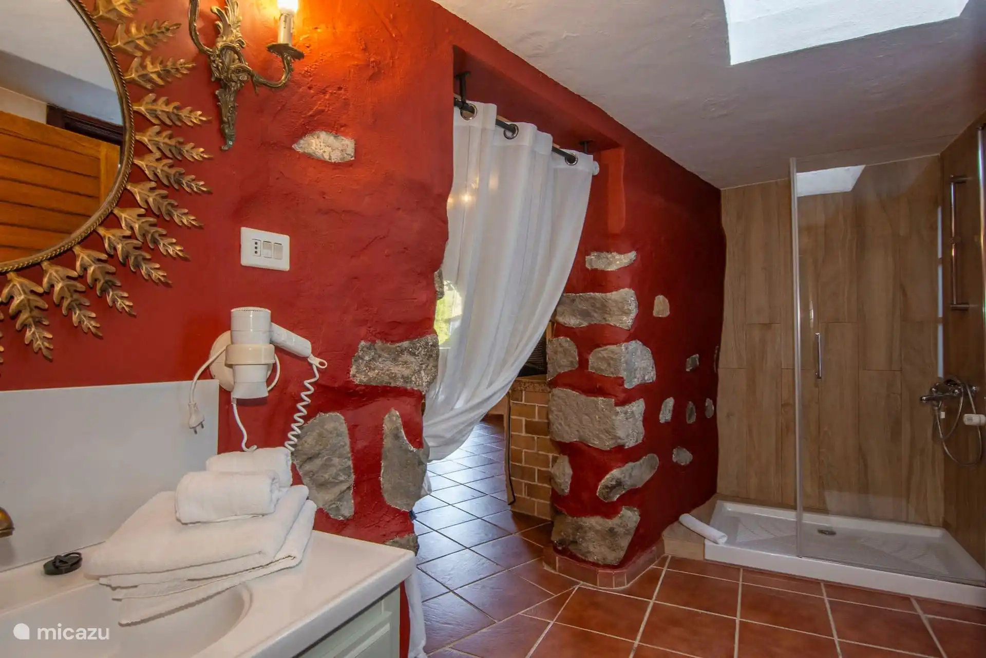 Badkamer met rode muur en decoratieve spiegel