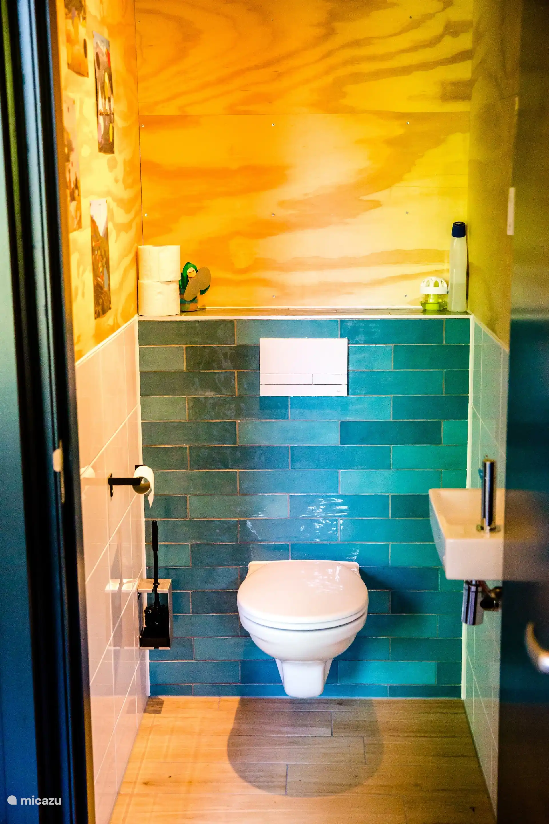 Toilet met sfeervolle turquoise tegelwand.