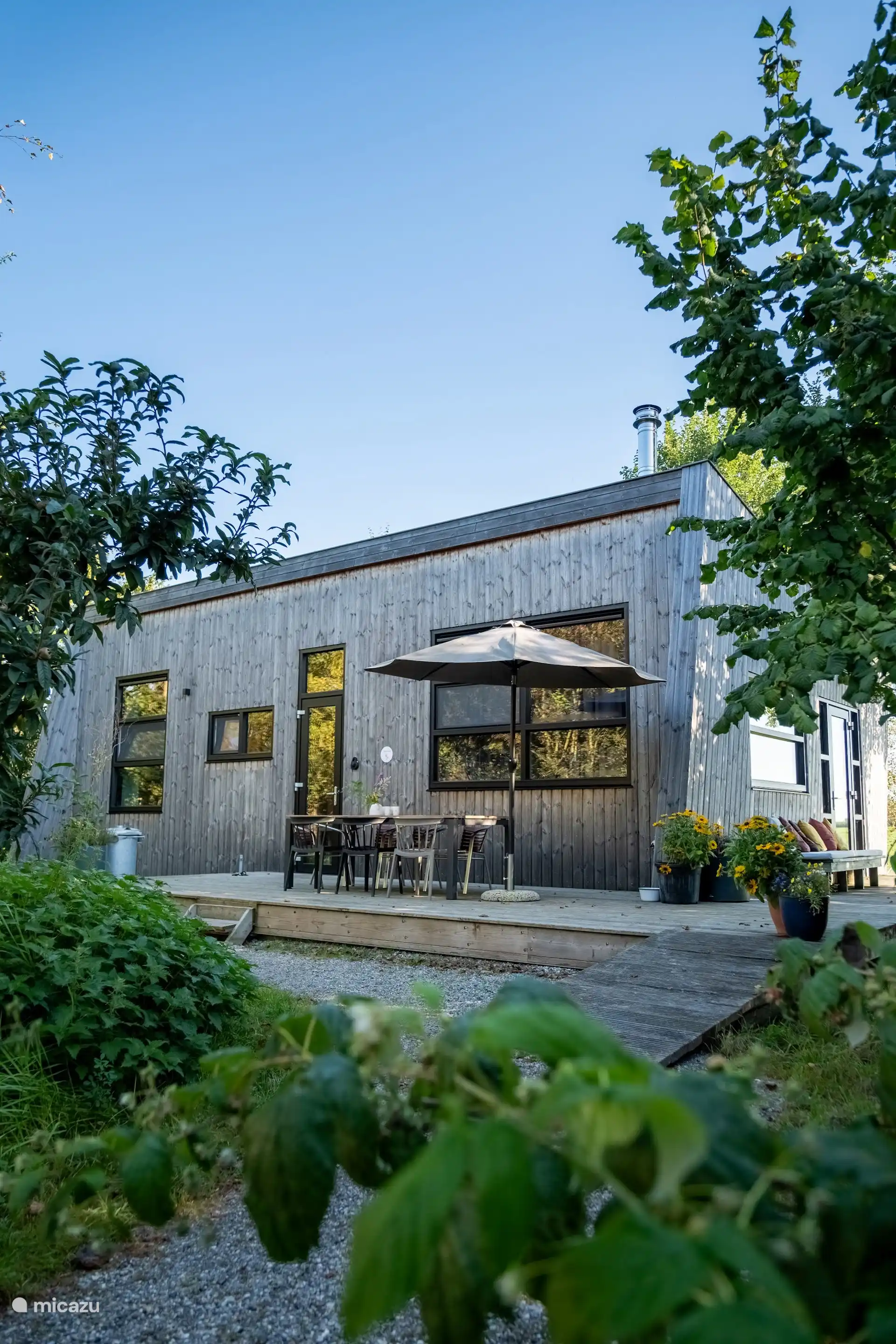 Het terras aan de tuinzijde van de lodge, met loungebank en zicht op het landschap.