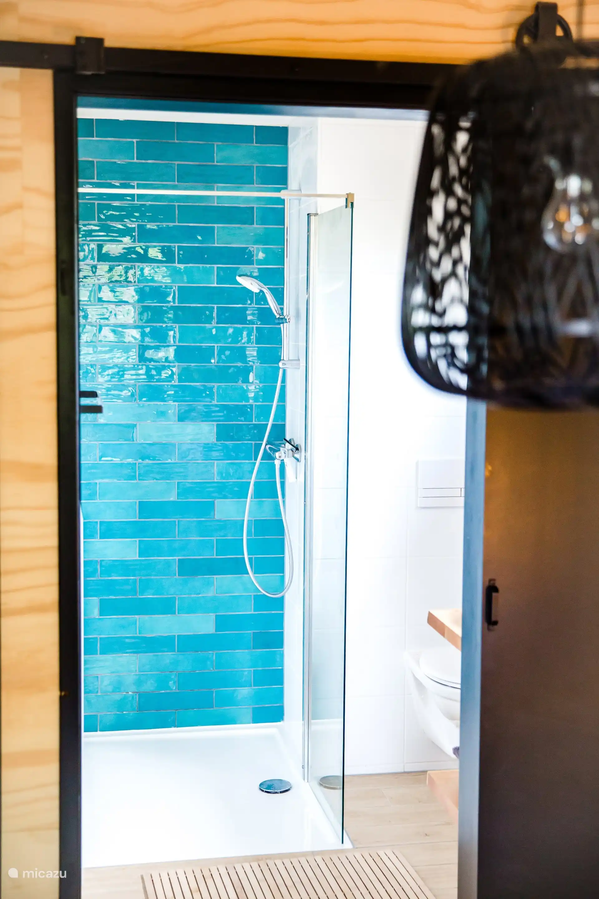 Inloopdouche met turquoise tegels, ruim en licht ingericht.