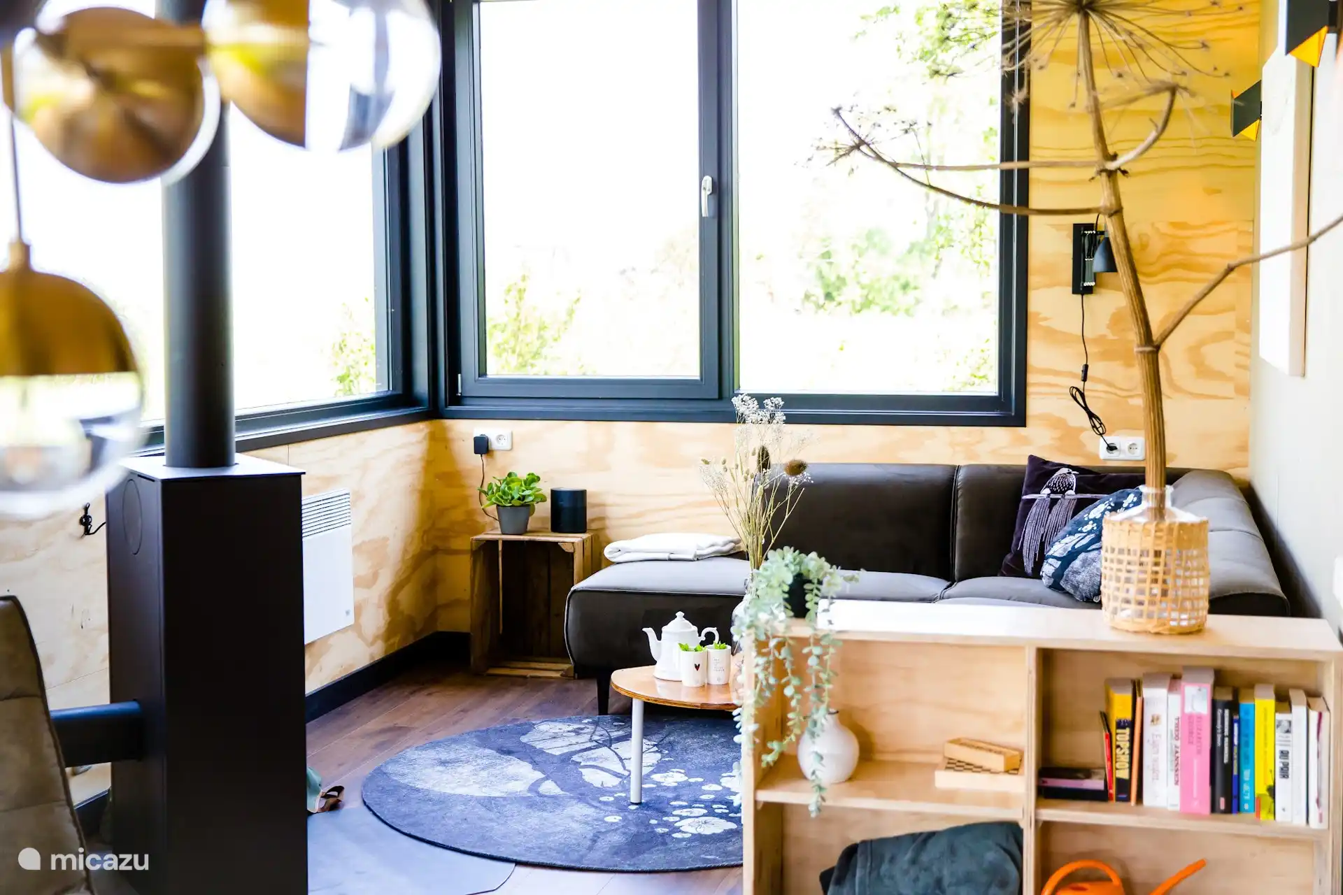 Sfeervolle woonkamer met houtkachel en gezellige zithoek, met natuurlijk hout en een groot raam met uitzicht.