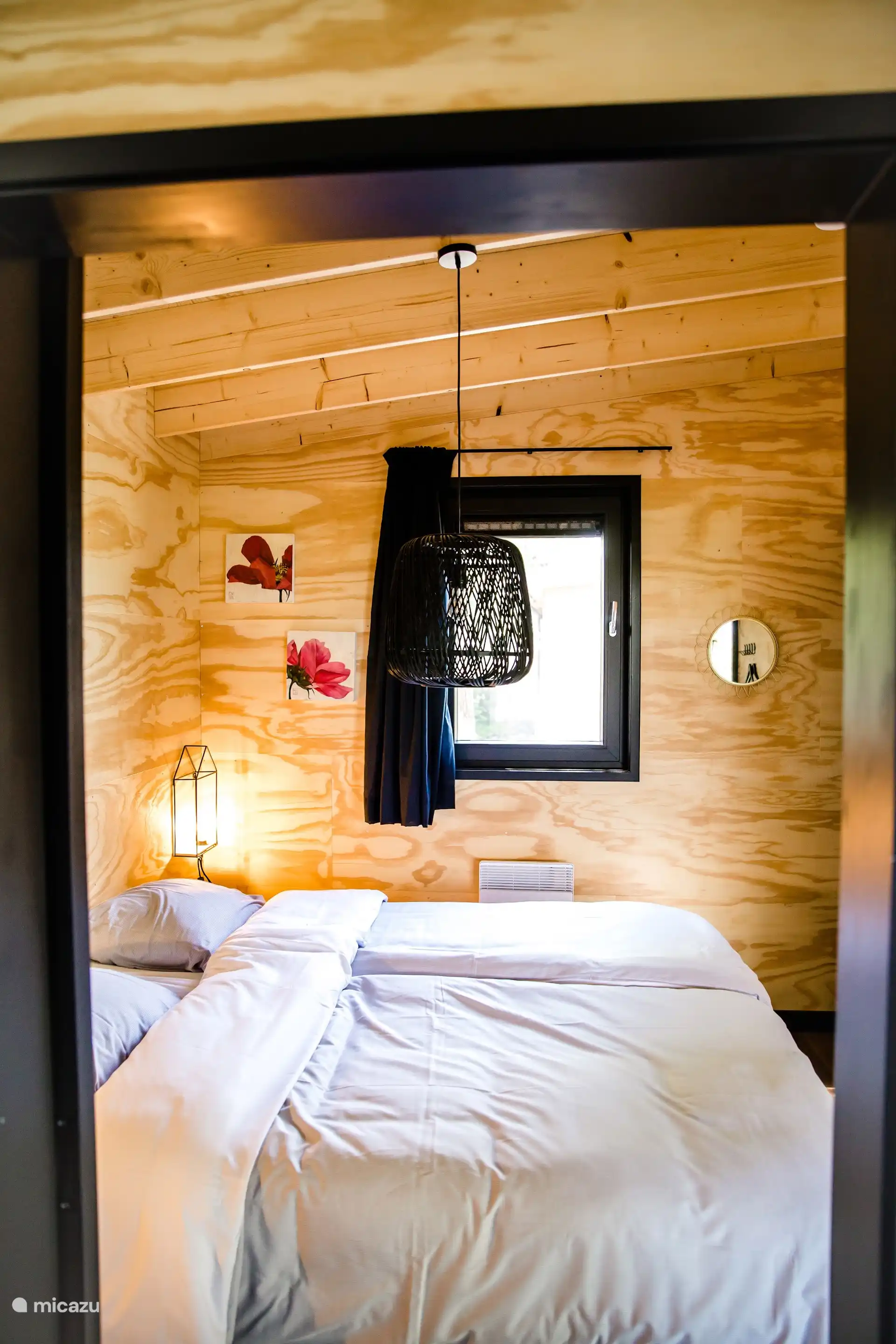 Slaapkamer met comfortabel tweepersoonsbed, sfeervolle verlichting en natuurlijk houten wanden.