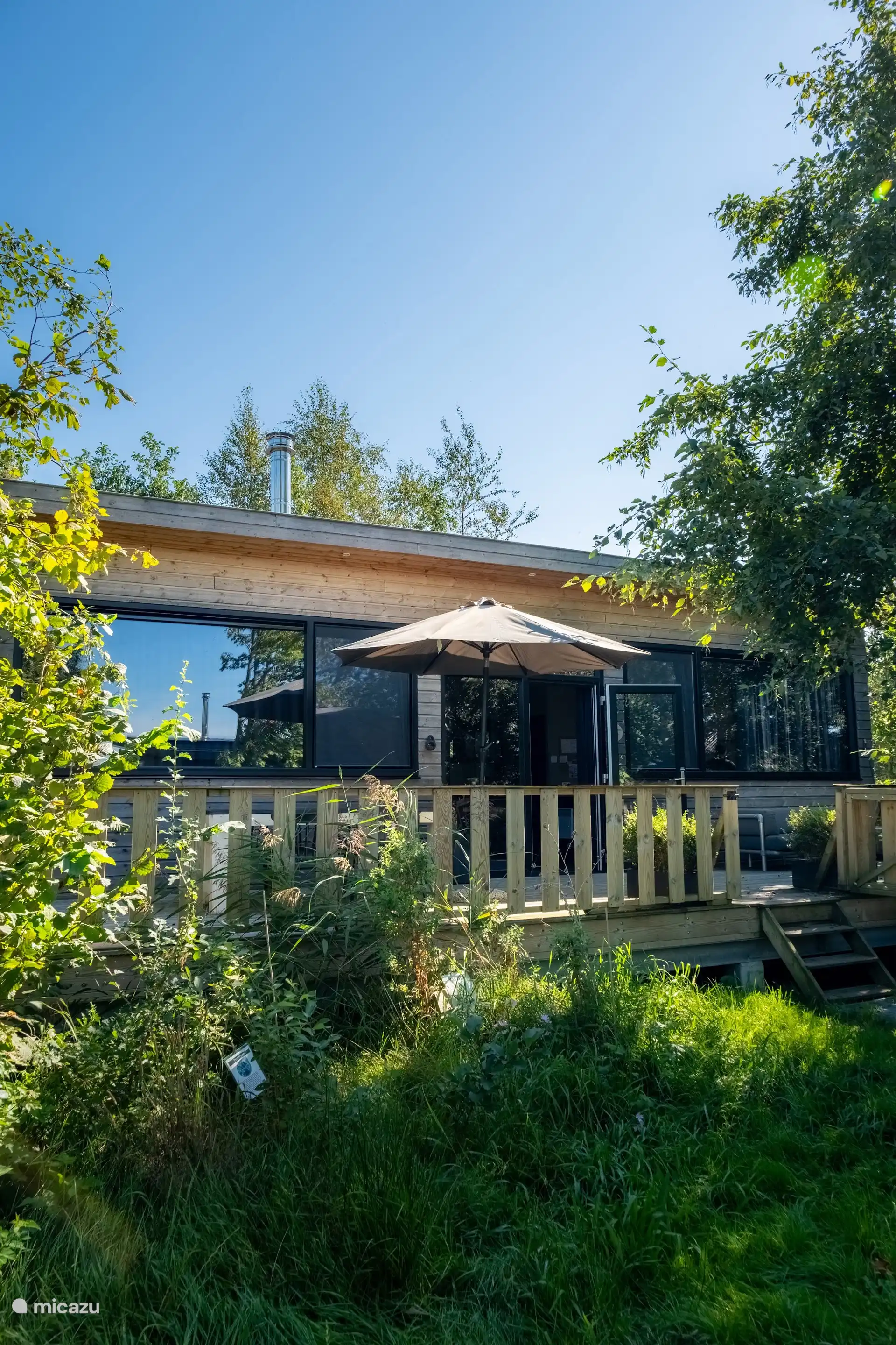 Het terras aan de tuinzijde van de lodge, met loungeset en uitzicht op het groen.