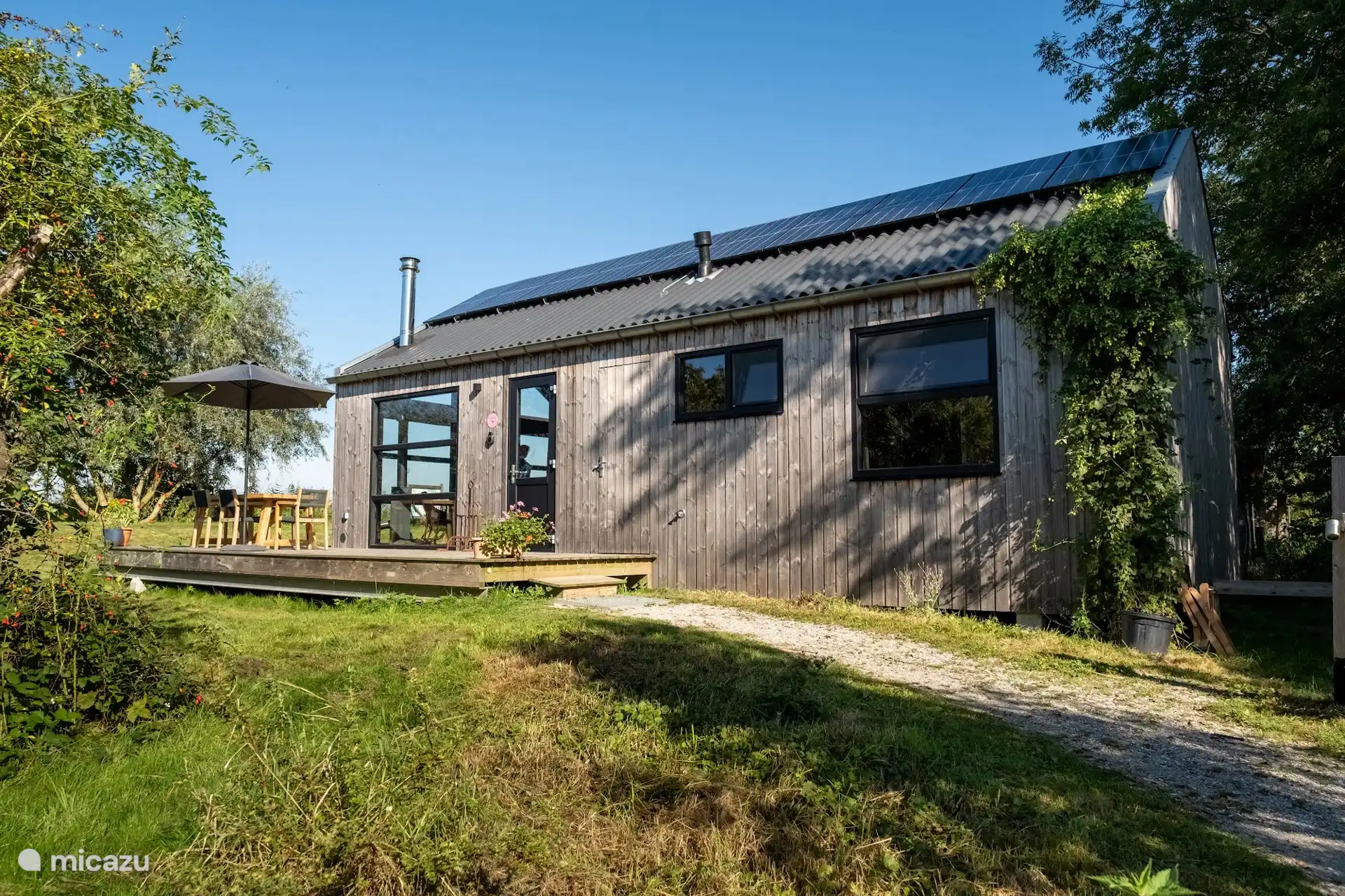 De houten lodge gezien vanaf de tuinzijde, met terras en veel privacy.