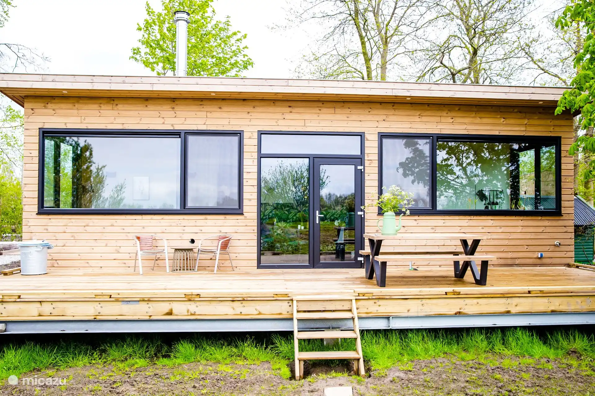 Het terras aan de tuinzijde van de lodge, met zitje en uitzicht over het groen van het park.