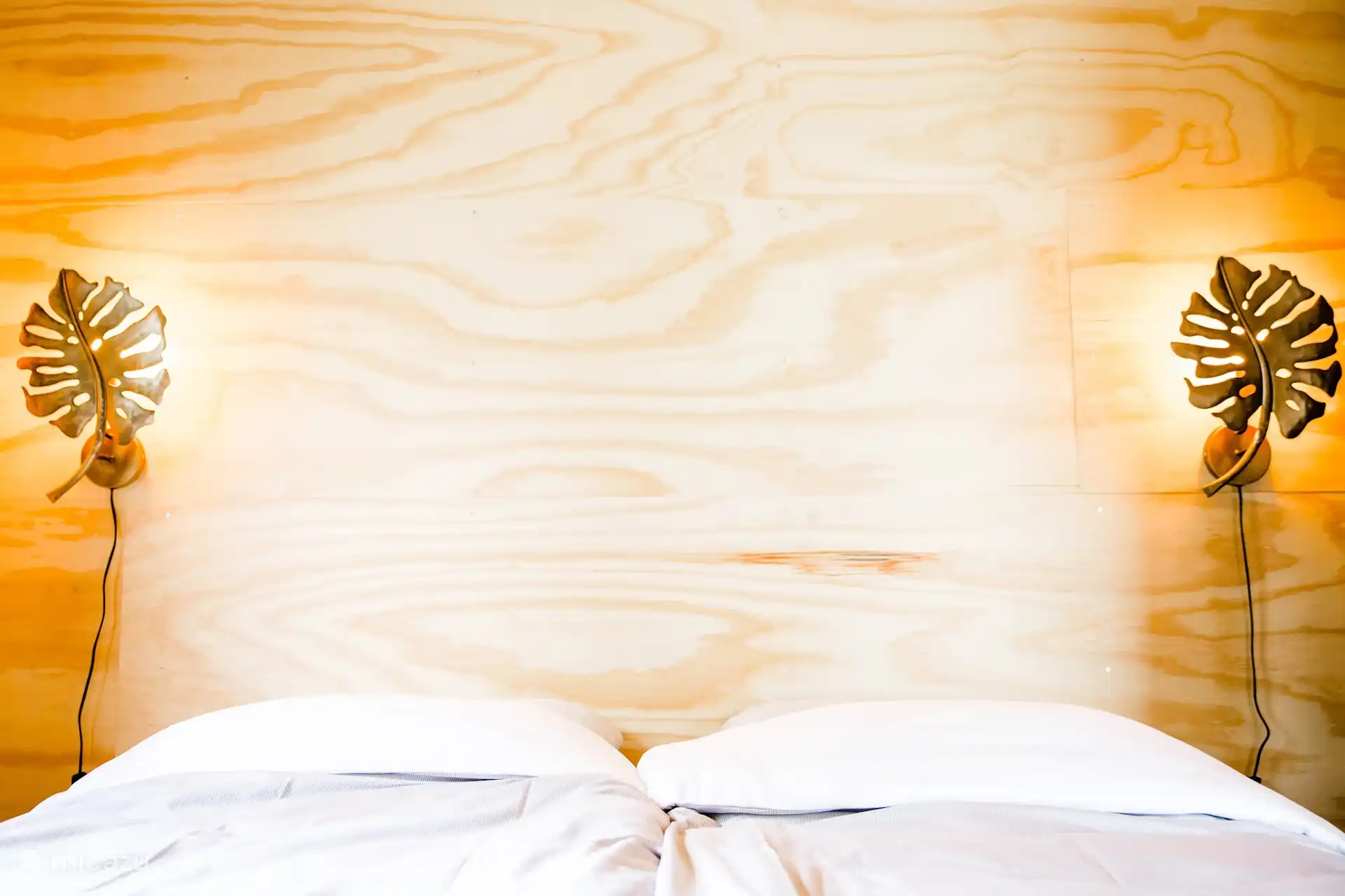 Sfeervolle slaapkamer met tweepersoonsbed, verlichting aan weerszijden van het bed.