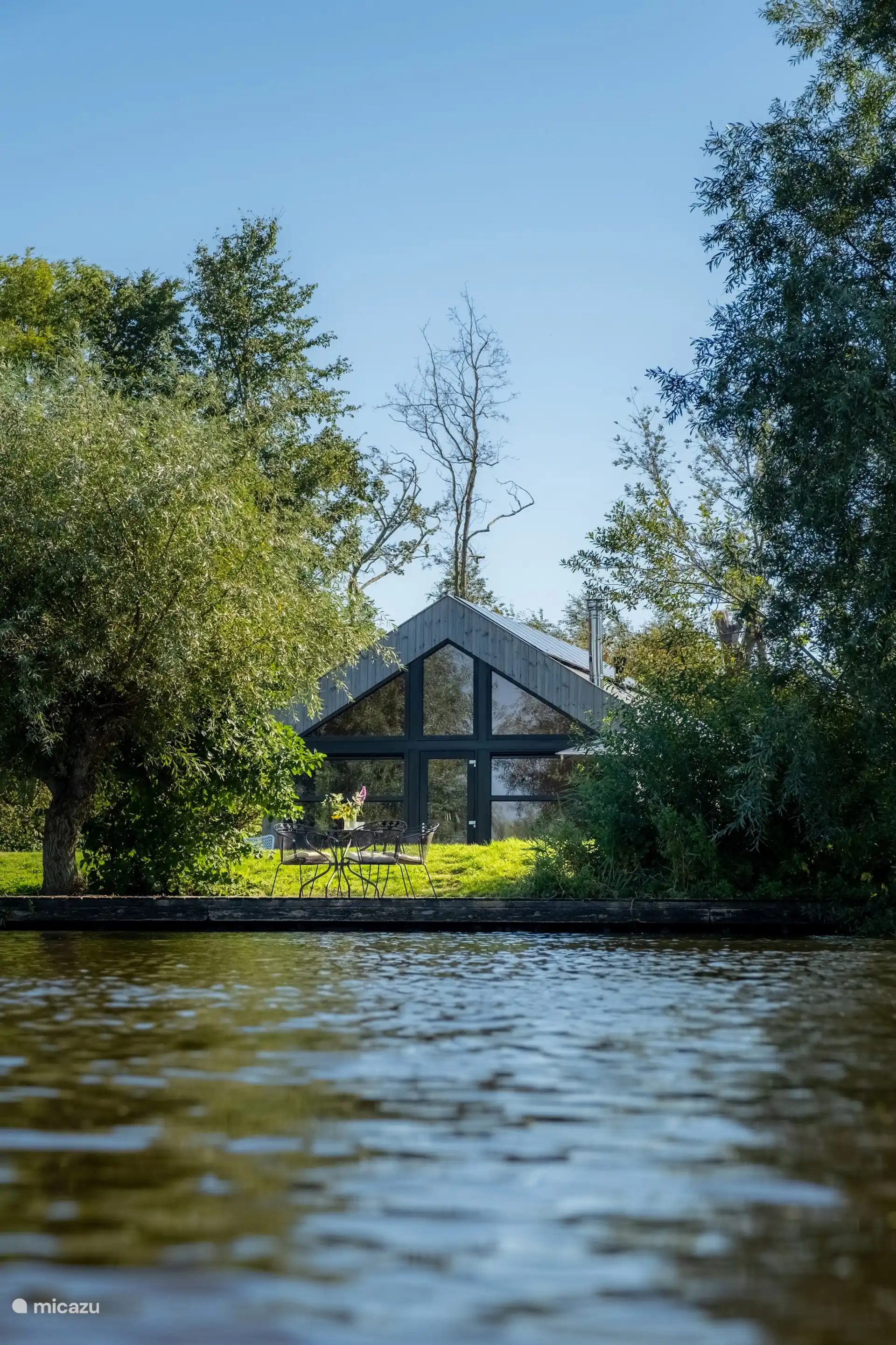 De lodge gezien vanaf de waterkant, omringd door groen.
